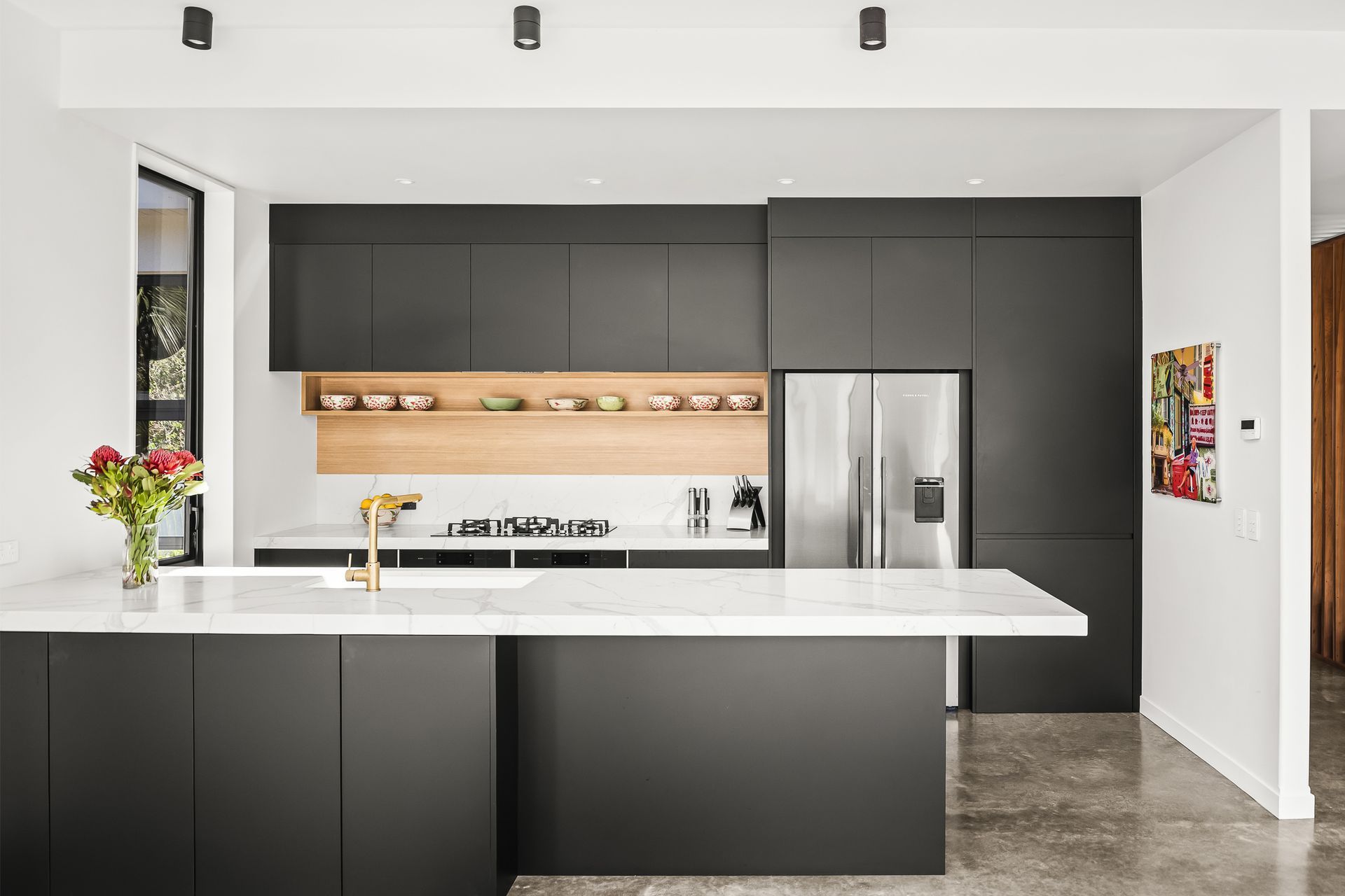 Calacatta Supreme engineered stone benchtops have the elegance of marble but are more durable. Brushed-brass tapware is a classic counterpoint to the sleek black laser-edge cabinetry.