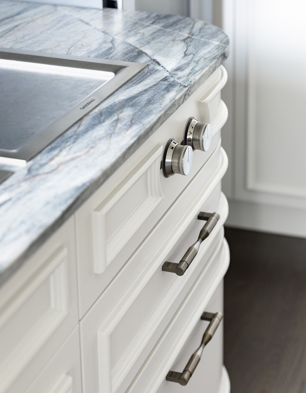 Framing the function, the round teppanyaki knobs are encircled with this moulding which then cleverly hugs the curve towards the ovens.  Echoed above on the rangehood panel, the face mouldings likewise follow the curved form softly reflecting morning light into the kitchen room; emphasising light and shadow.