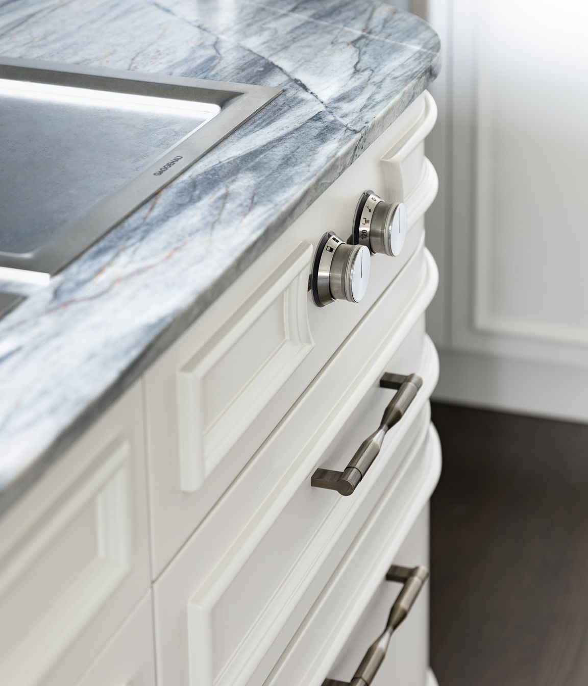 Framing the function, the round teppanyaki knobs are encircled with this moulding which then cleverly hugs the curve towards the ovens.  Echoed above on the rangehood panel, the face mouldings likewise follow the curved form softly reflecting morning light into the kitchen room; emphasising light and shadow.