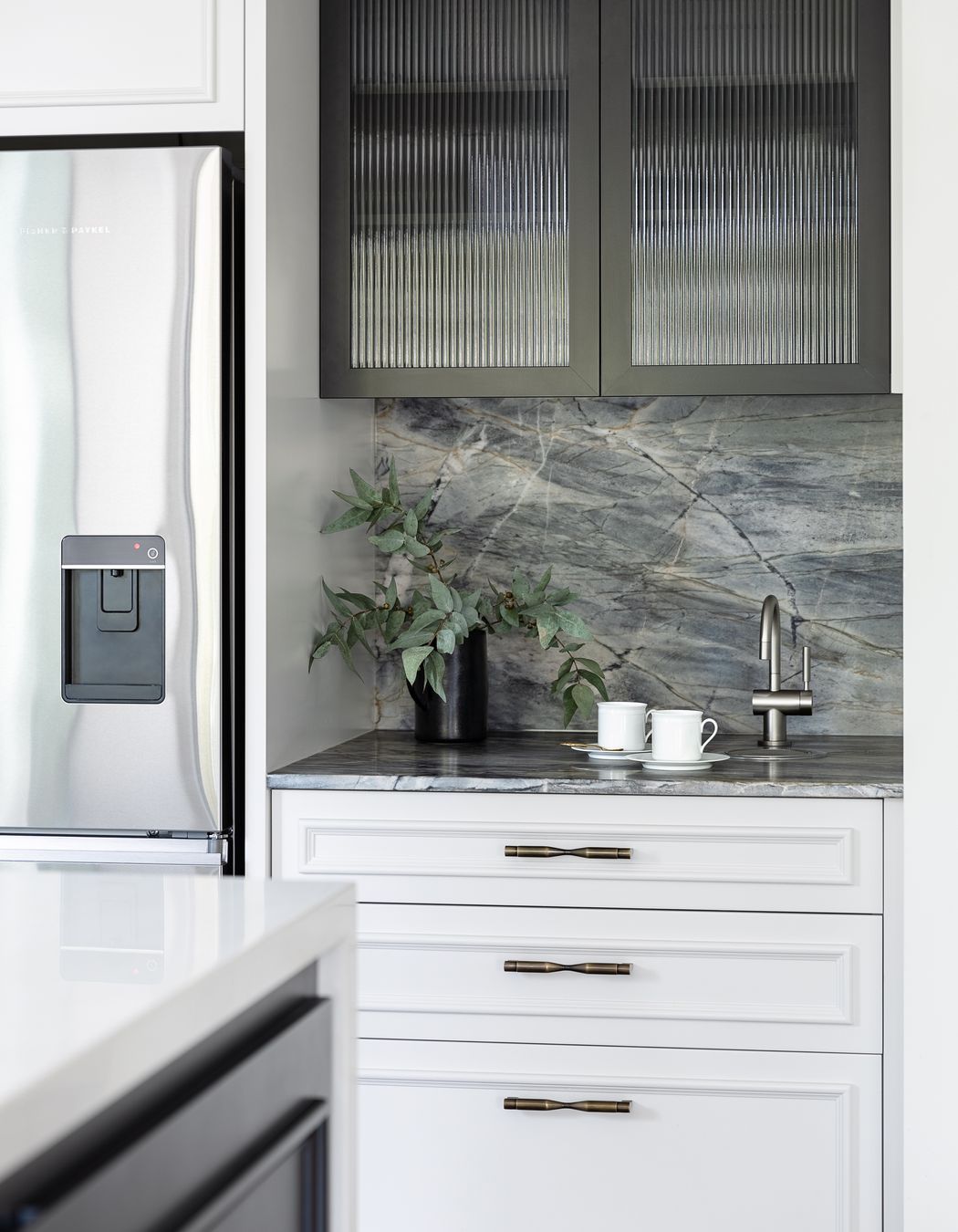 The dedicated coffee zone integrates a hot water tap; another workspace for family to independently prepare. The custom black steel frame and reeded glass are mirrored here to match the table support.