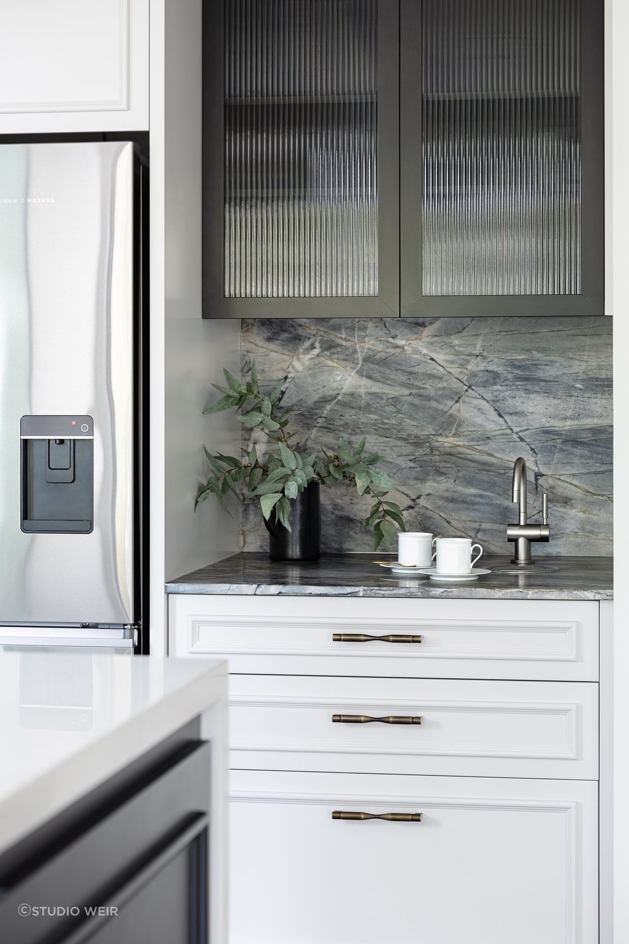 The dedicated coffee zone integrates a hot water tap; another workspace for family to independently prepare. The custom black steel frame and reeded glass are mirrored here to match the table support.