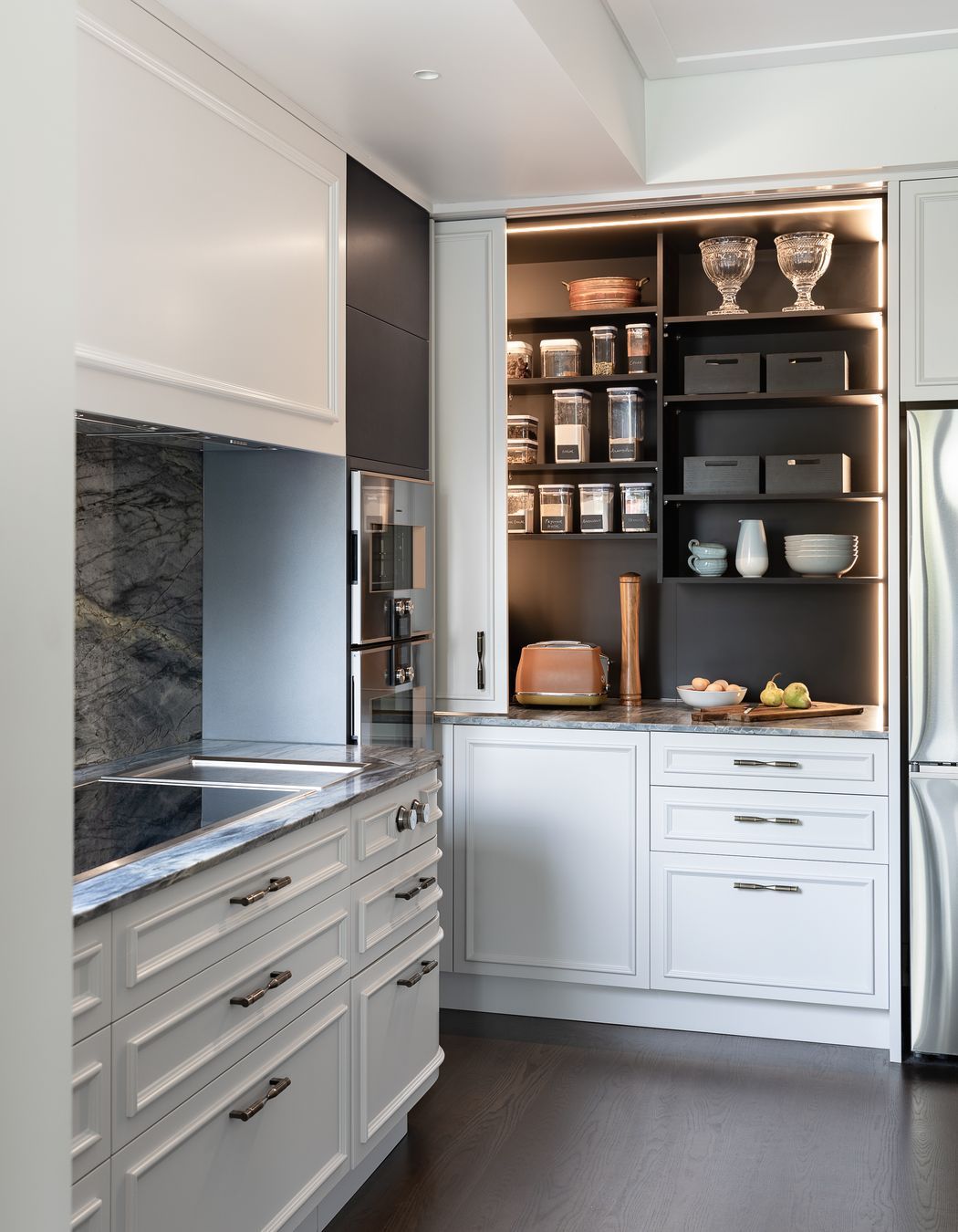 A generous pantry with deep benches hides small appliances inside.  Integrated vertical sensor lighting is incorporated here.