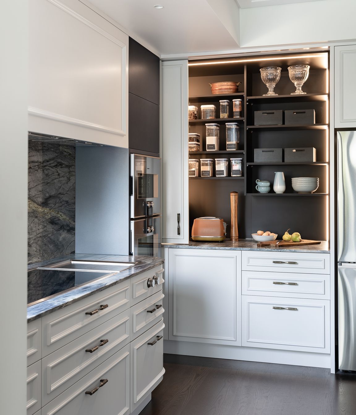 A generous pantry with deep benches hides small appliances inside.  Integrated vertical sensor lighting is incorporated here.
