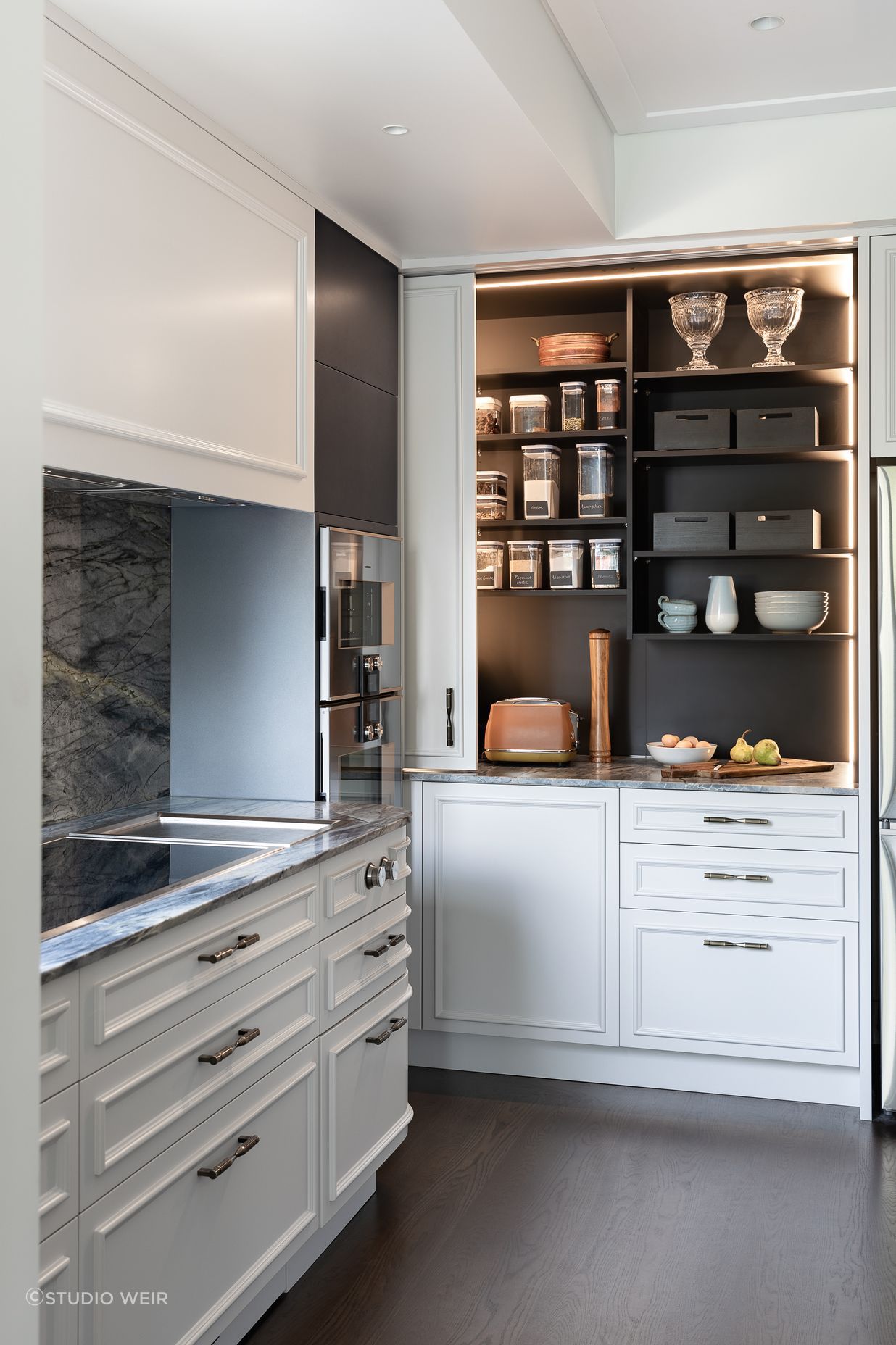 A generous pantry with deep benches hides small appliances inside.  Integrated vertical sensor lighting is incorporated here.