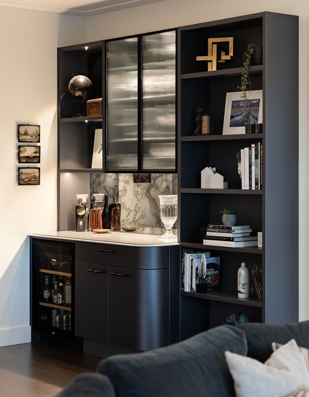 Continuing the elegant shimmering navy palette, the reeded glass, ogee edge and gentle curves, Toni recommended replacing a timber bookcase with a built-in bar and display wall.