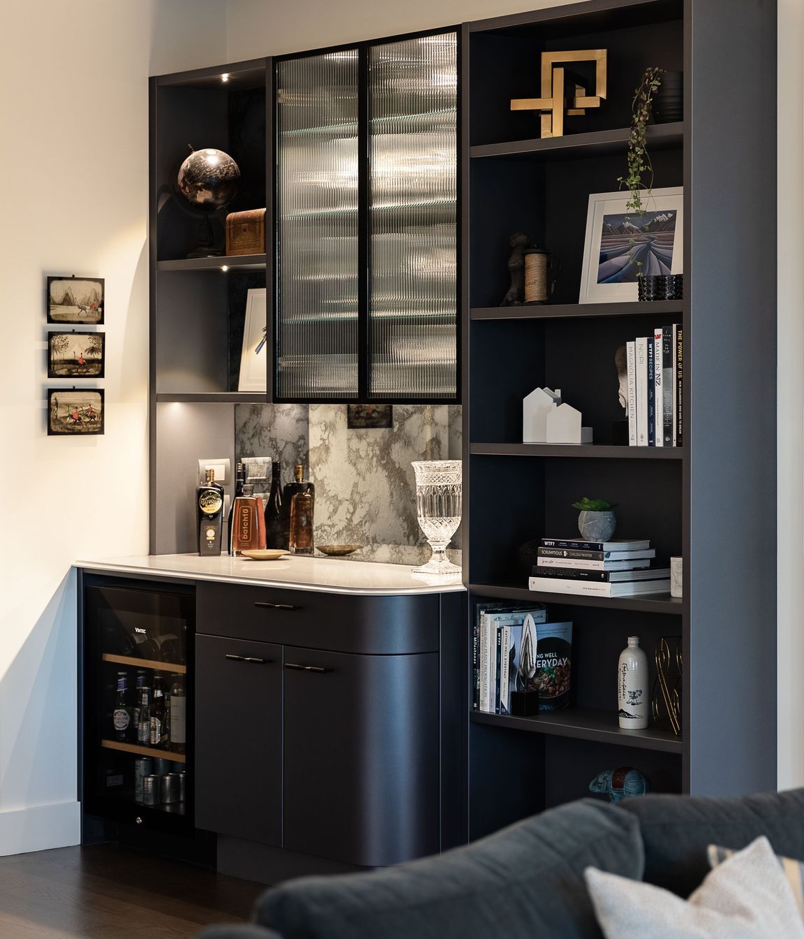 Continuing the elegant shimmering navy palette, the reeded glass, ogee edge and gentle curves, Toni recommended replacing a timber bookcase with a built-in bar and display wall.