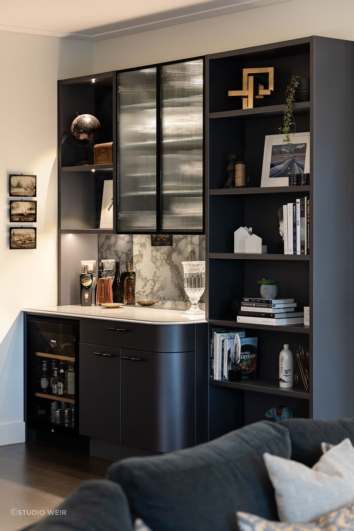Continuing the elegant shimmering navy palette, the reeded glass, ogee edge and gentle curves, Toni recommended replacing a timber bookcase with a built-in bar and display wall.
