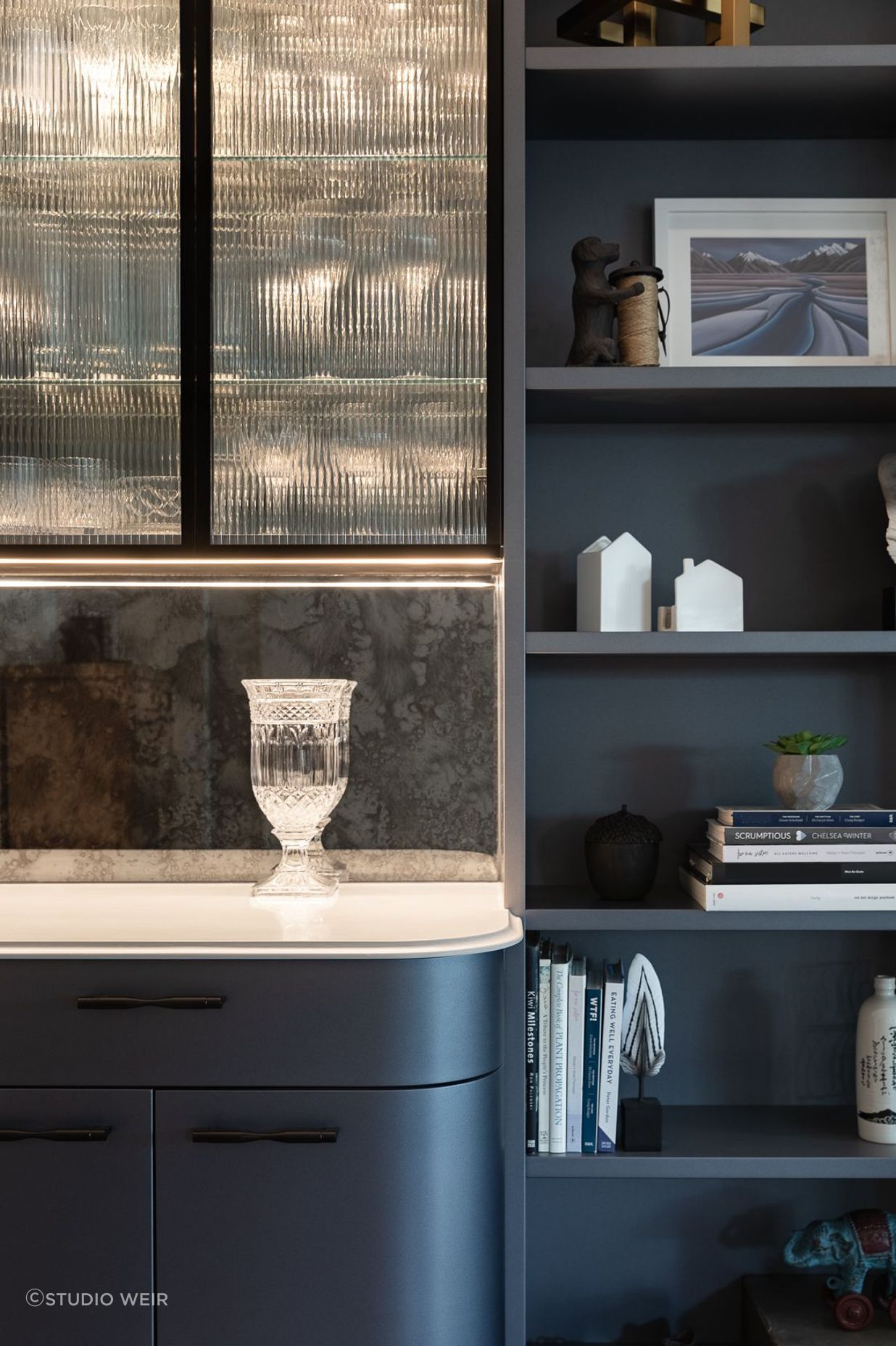 Exquisite lines and curated soft lighting completes the sophisticated design. Located opposite the kitchen, the bar leads on to an outdoor entertainment room complete with fireplace, wall heaters, a movie screen and integrated BBQ.