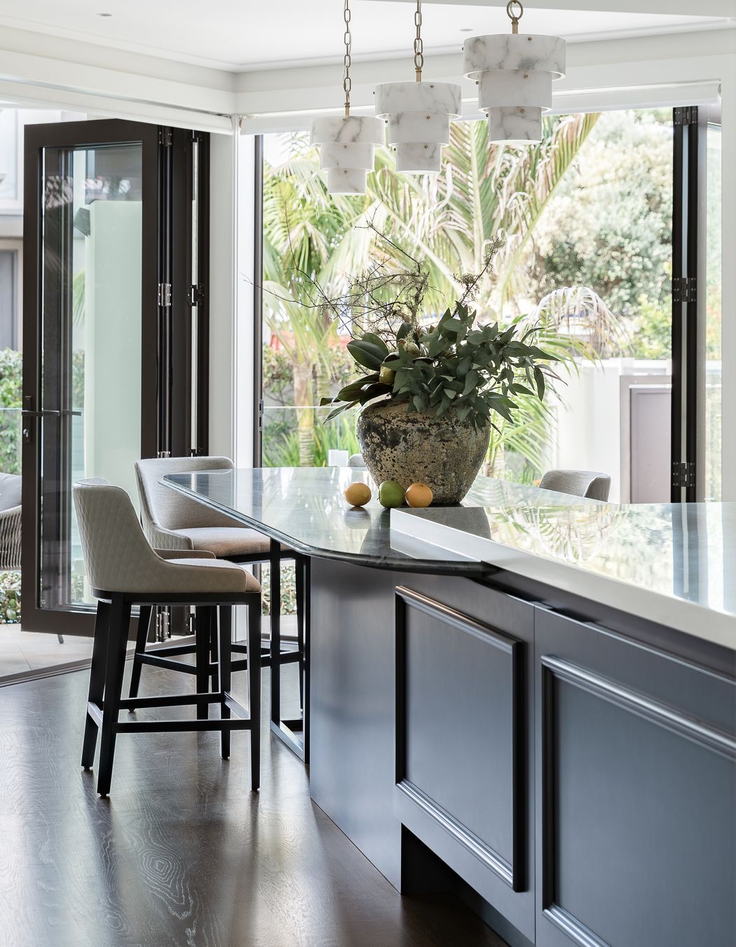 Vital storage continues under the island while casual dining to the table end offers visual connection to the pool and sun-drenched courtyard.