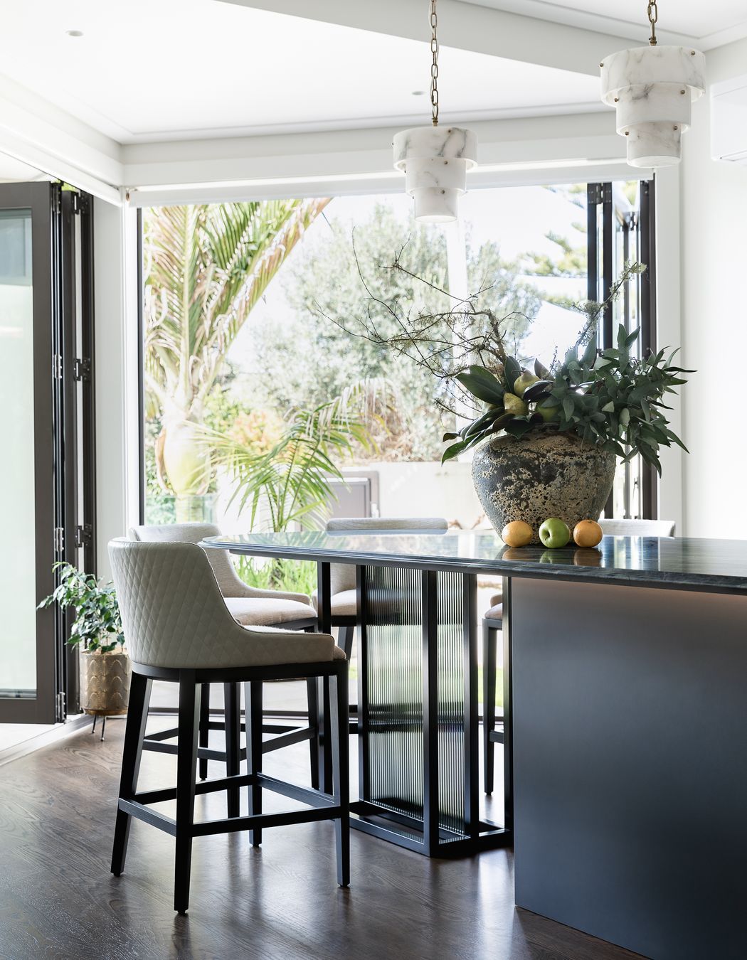 Supporting the table-island, Toni designed a custom black steel frame with back-to-back reeded glass insets, configured for safety and removability and sheathed in a smoke film for visual interest.  Integrated bead lighting below the table follows the curve.