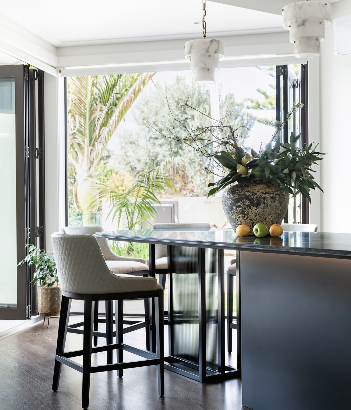 Supporting the table-island, Toni designed a custom black steel frame with back-to-back reeded glass insets, configured for safety and removability and sheathed in a smoke film for visual interest.  Integrated bead lighting below the table follows the curve.