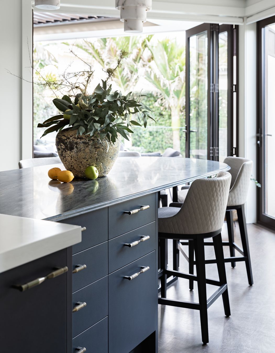 A key feature is the stunning navy-hued quartzite, complemented with a shimmery navy metallic and contrasting light joinery. The richly textural stone table has a unique ogee edge detail achieved with imported tooling and hand-finished.