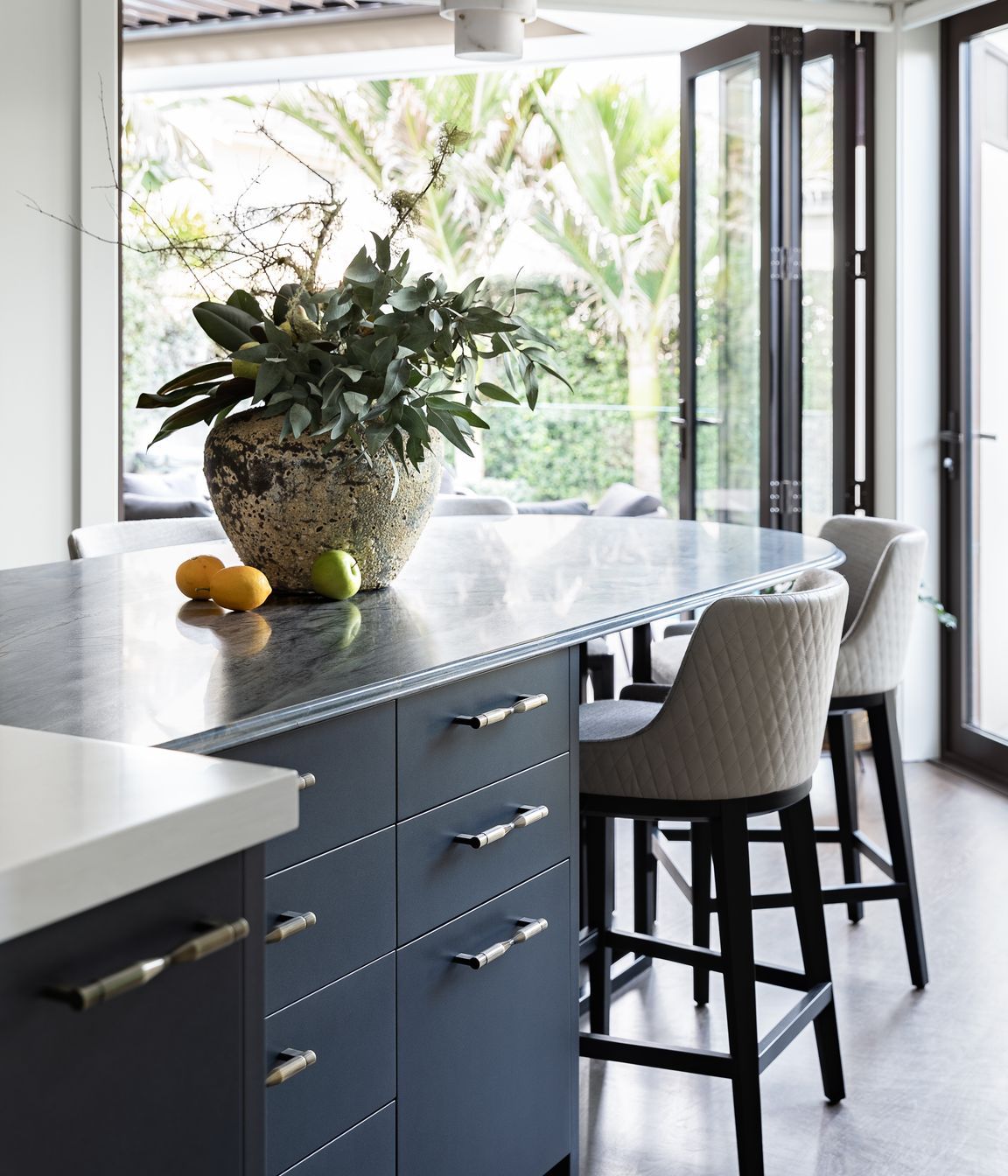 A key feature is the stunning navy-hued quartzite, complemented with a shimmery navy metallic and contrasting light joinery. The richly textural stone table has a unique ogee edge detail achieved with imported tooling and hand-finished.