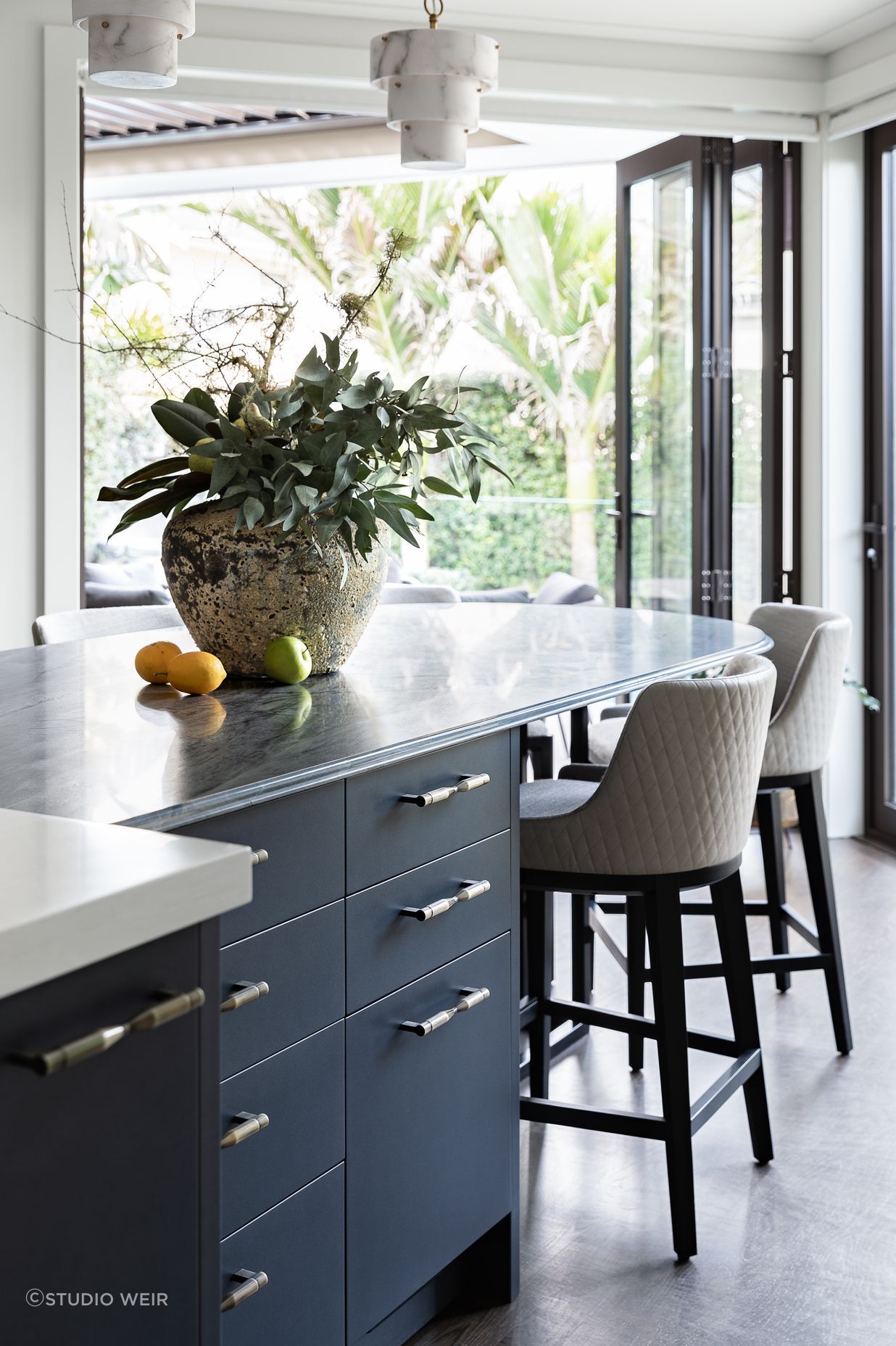 A key feature is the stunning navy-hued quartzite, complemented with a shimmery navy metallic and contrasting light joinery. The richly textural stone table has a unique ogee edge detail achieved with imported tooling and hand-finished.