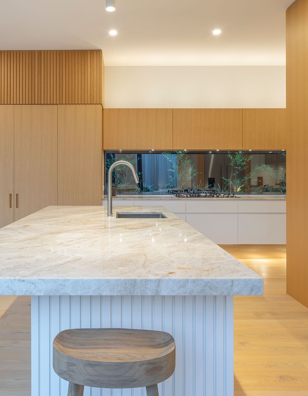 Bench tops feature an elegantly patterned quartzite, chosen for its serene beauty and earth-real character. Hand-picked at the suppliers, the Champagne stone with its textural grain and golden hues complement the oak cabinetry and waterbourne-finished floors beautifully.