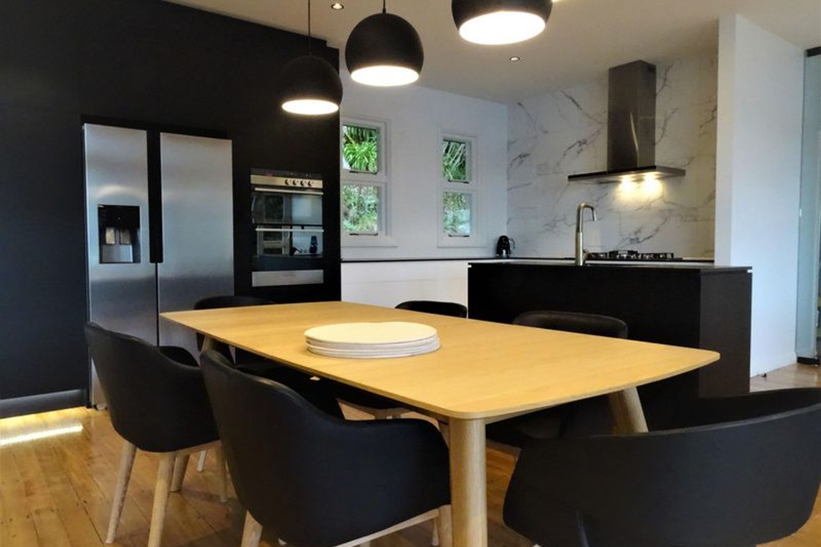The black cabinetry, lighting and marble splash back tie in together