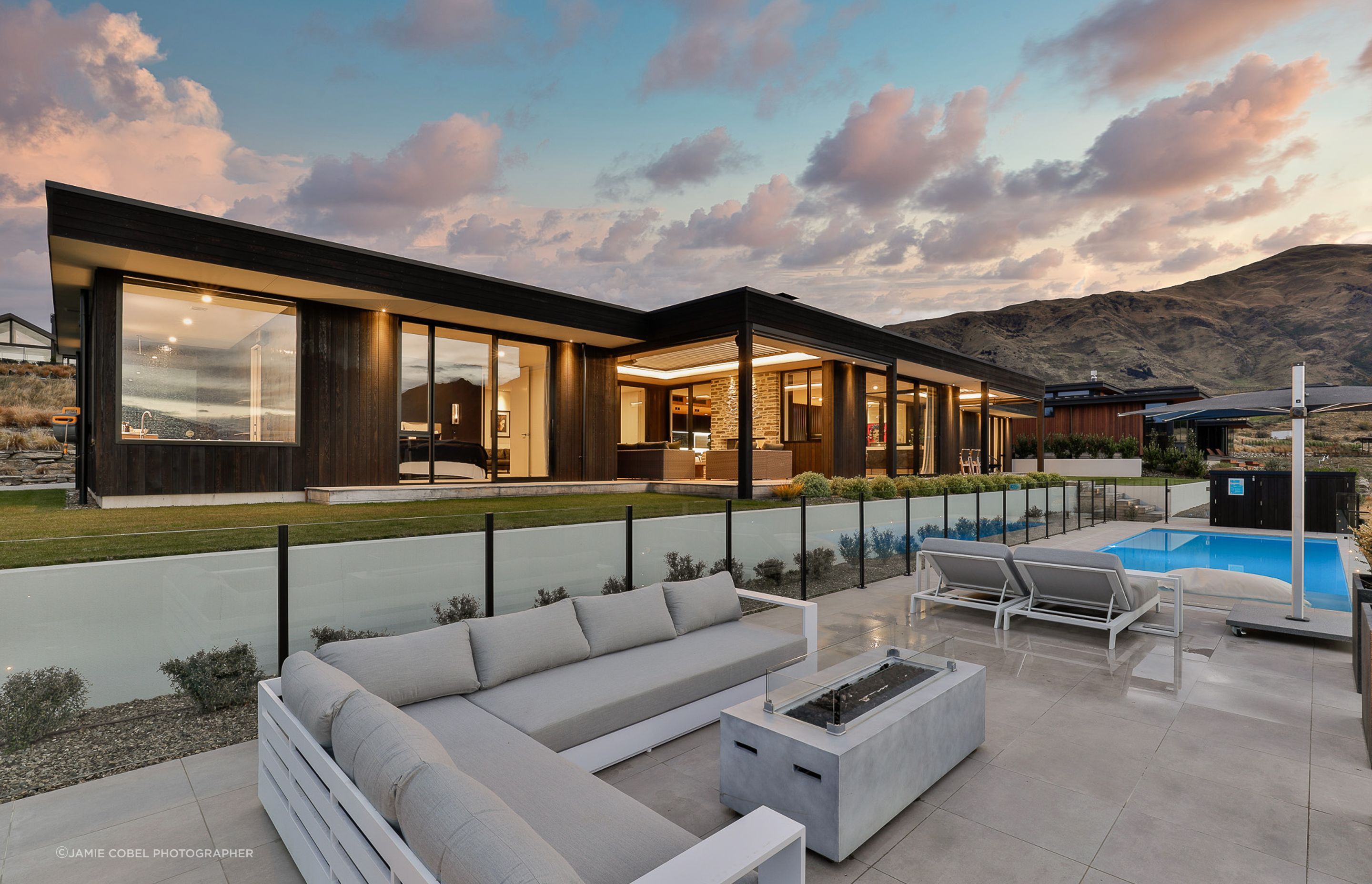 Exterior by night, featuring pool and entertainment space. Interior Design- Kelly @ Archi Build Ltd. Landscaping- by Tim at The Landscaper Wanaka.
