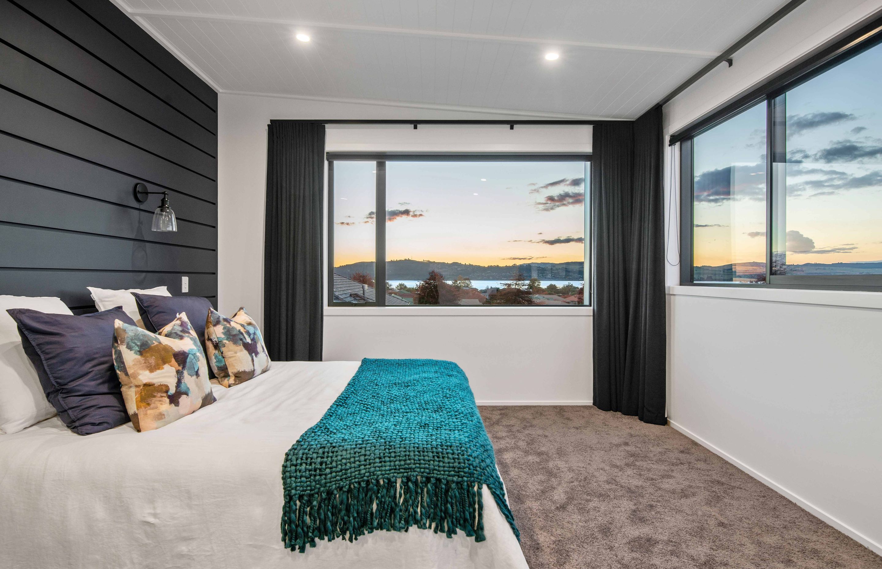 Upstairs, the main bedroom enjoys double-aspect views of the lake and continues the bold black and white theme with accent colours.
