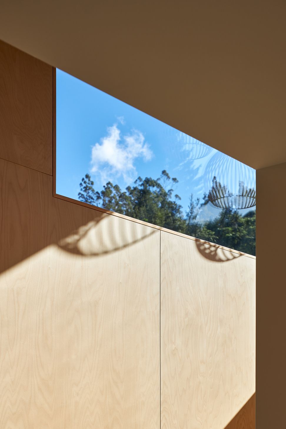 Bathed in natural light from expansive windows, the stairwell becomes more than a circulation space. Birch plywood walls and a finely crafted oak screen bring warmth and texture, while sculptural timber pendant lights provide a striking focal point. Together, the carefully composed materials and abundant daylight create a welcoming, gallery-like space that connects the home's levels with a sense of openness and calm.