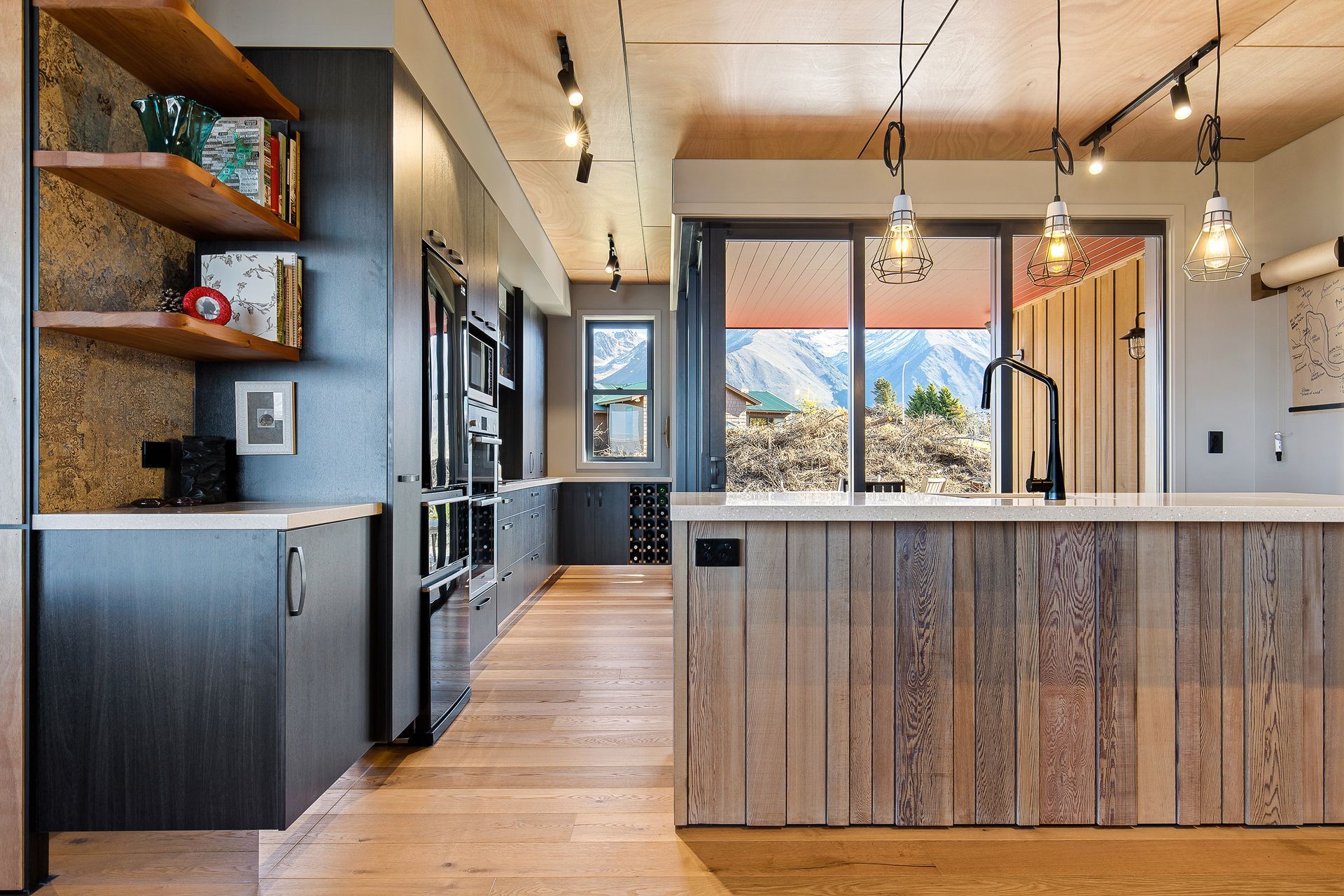 Timber panelling on the front of the island echoes the exterior cladding, and Orlando Steel Matt Black Grill pendants add an industrial edge.