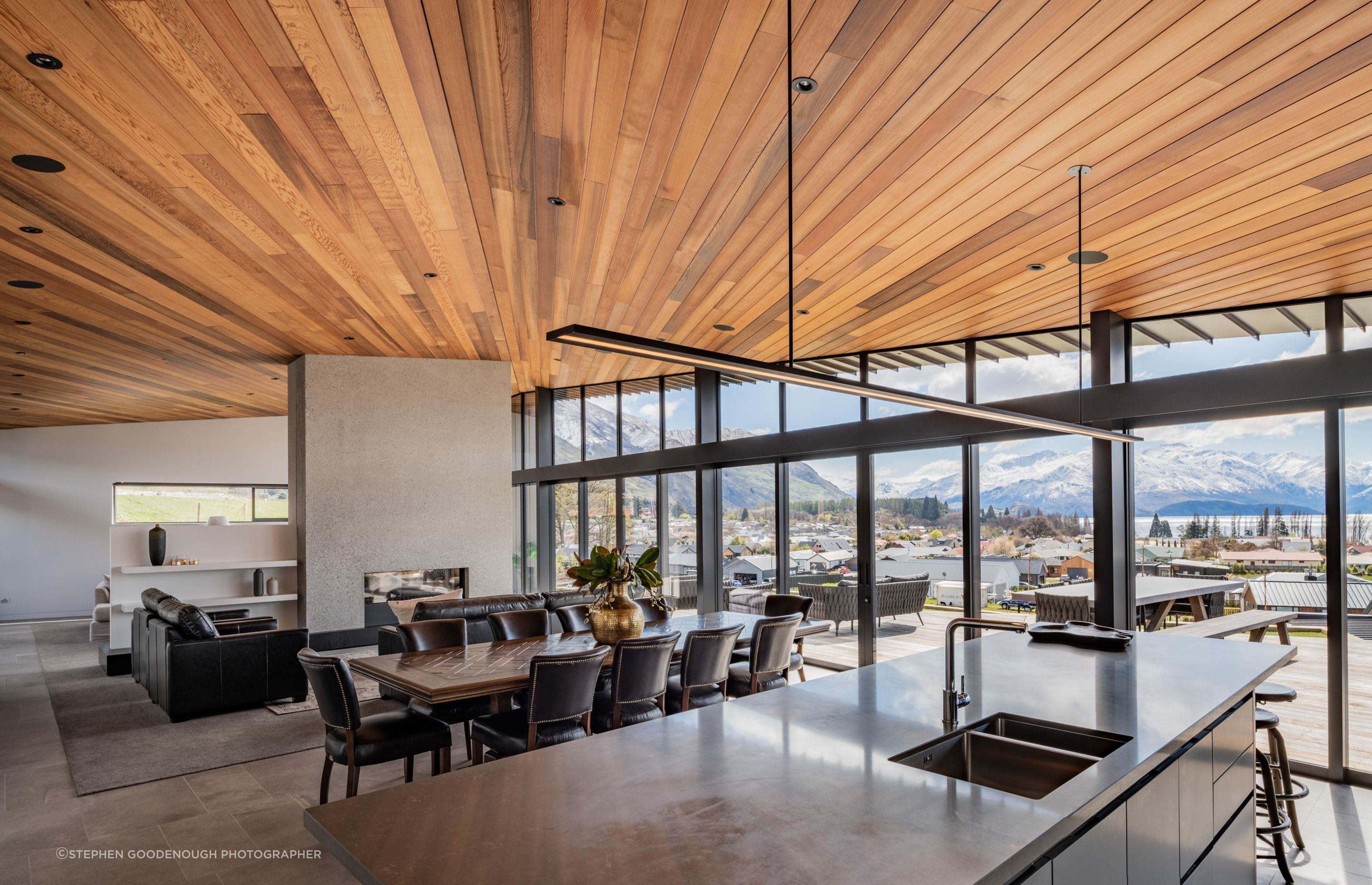 A concrete wall with double-sided gas fireplace separates the living space from a TV lounge.