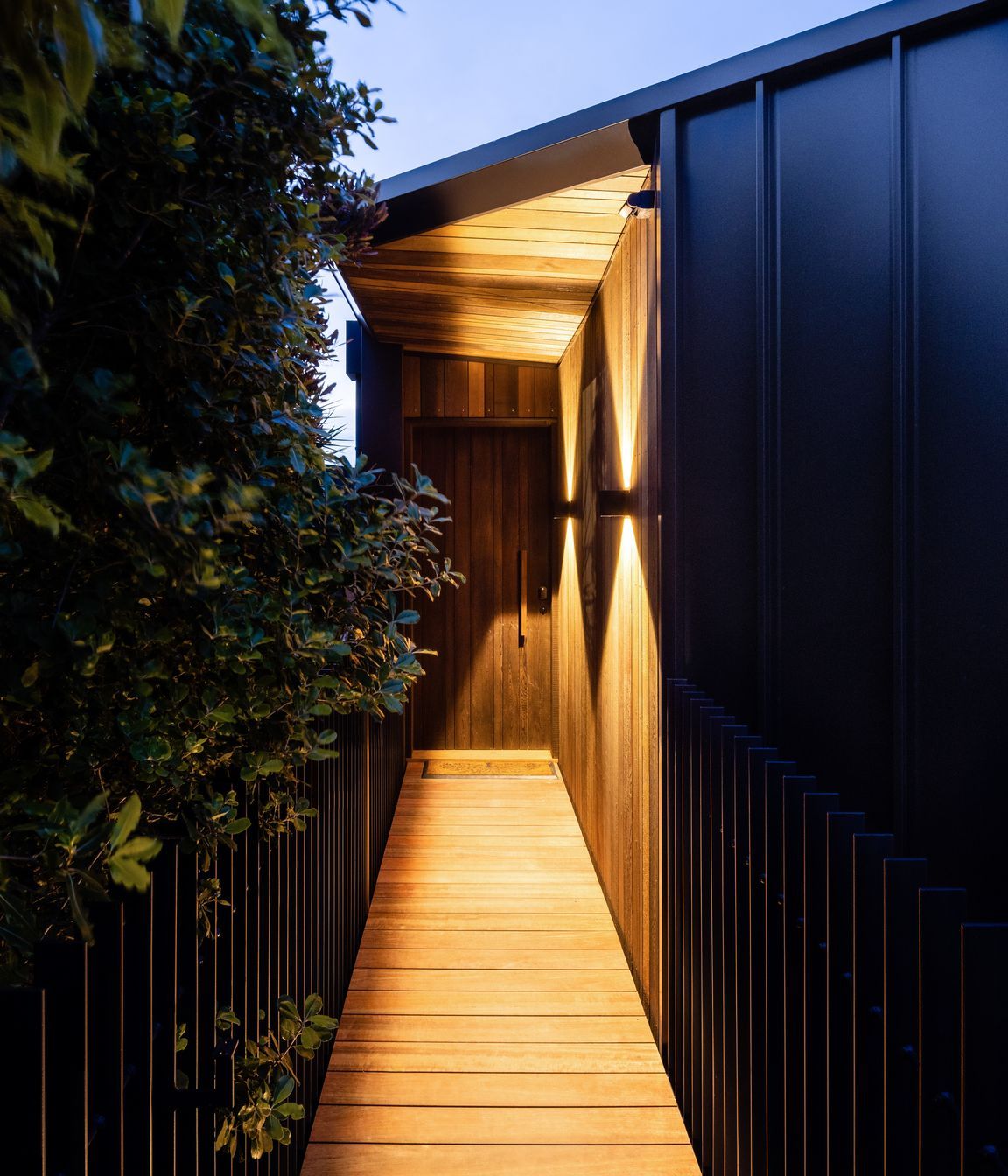 Approaching the entry, the boardwalk is lit up, casting sculptural shadows on the home.
