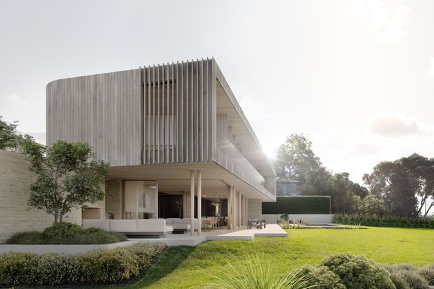 Contemporary two-storey residential building with a strongly cantilevered upper volume, vertical timber-like screening, pale masonry or rendered walls, and extensive glazing. The ground level opens onto a landscaped lawn and covered outdoor terrace, while mature planting and clipped garden beds frame the home.