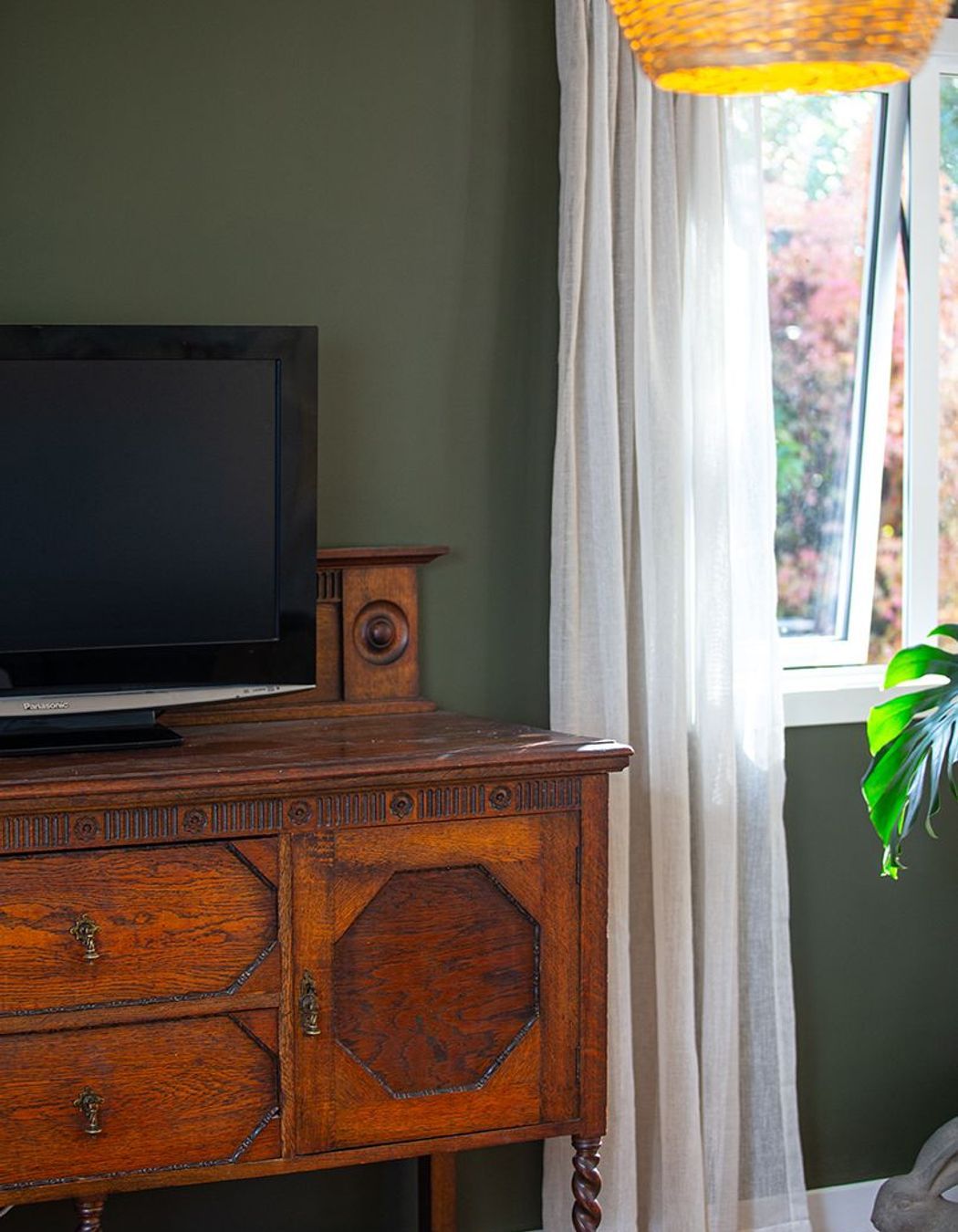A turn of the century oak washstand with detailed panelling and turned legs looks amazing with walls in Resene 'Scrub' and soft linen curtains.