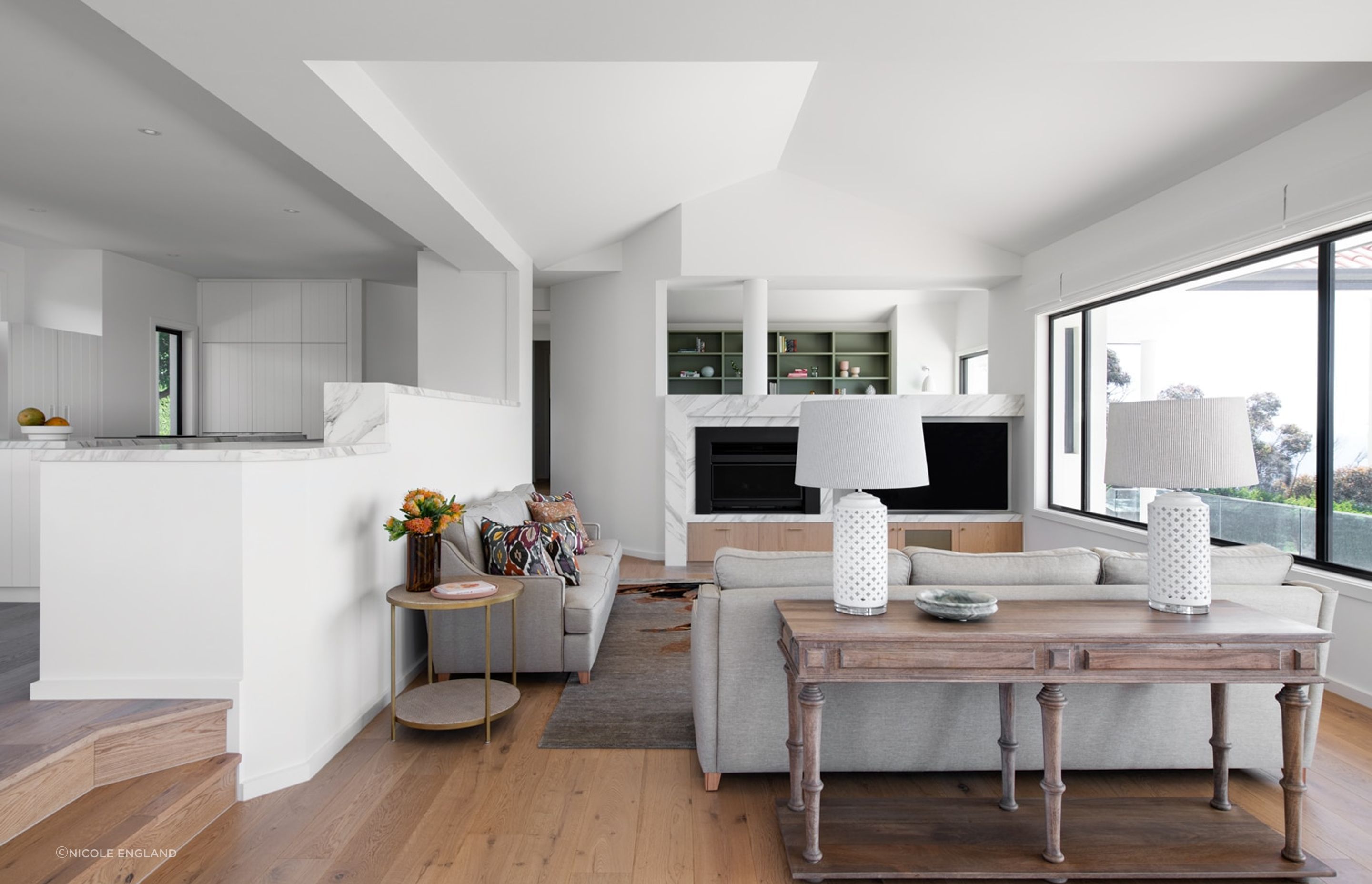 Open plan interior design featuring a fireplace & custom joinery.