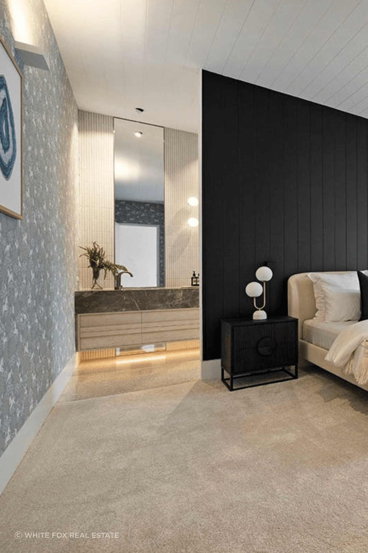 The master bedroom entrance to the ensuite is illuminated by uplights and large mirrors