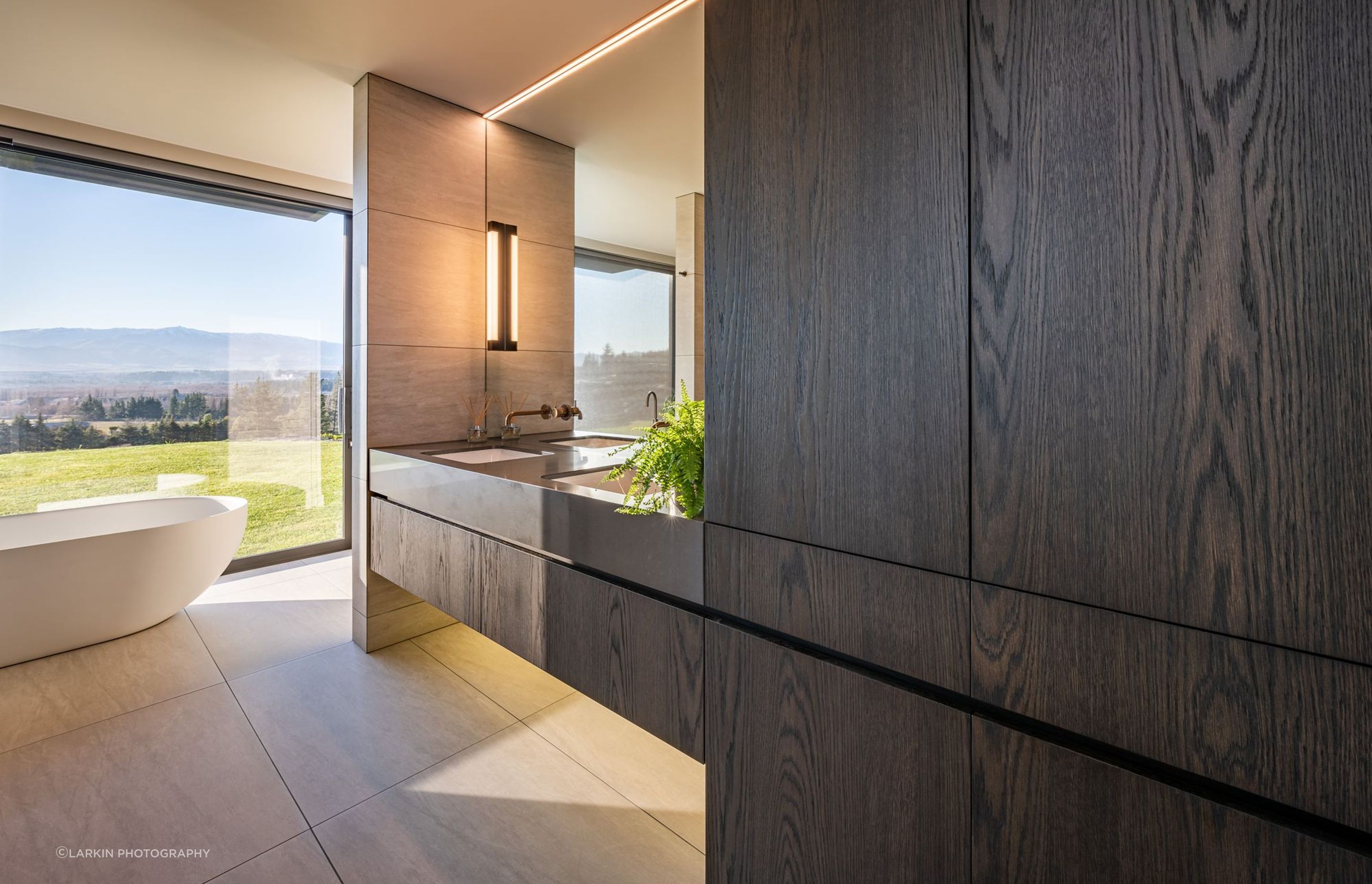 Dark oak laminate cabinetry and double sinks bring a dramatic yet earthy element to the master en suite.