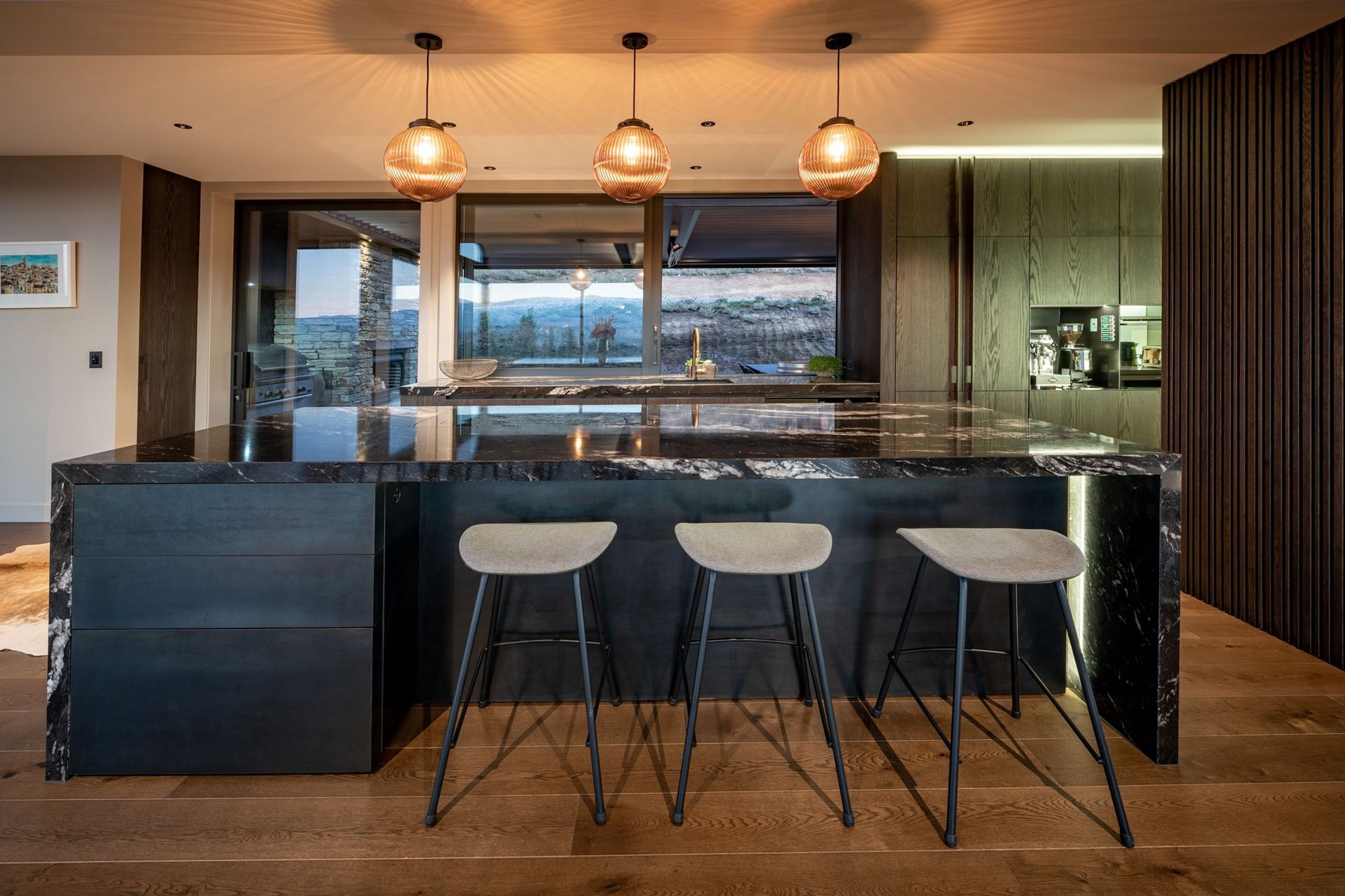 The dramatic granite kitchen island synchronises beautifully with the schist chimney in the covered courtyard space directly behind the kitchen.