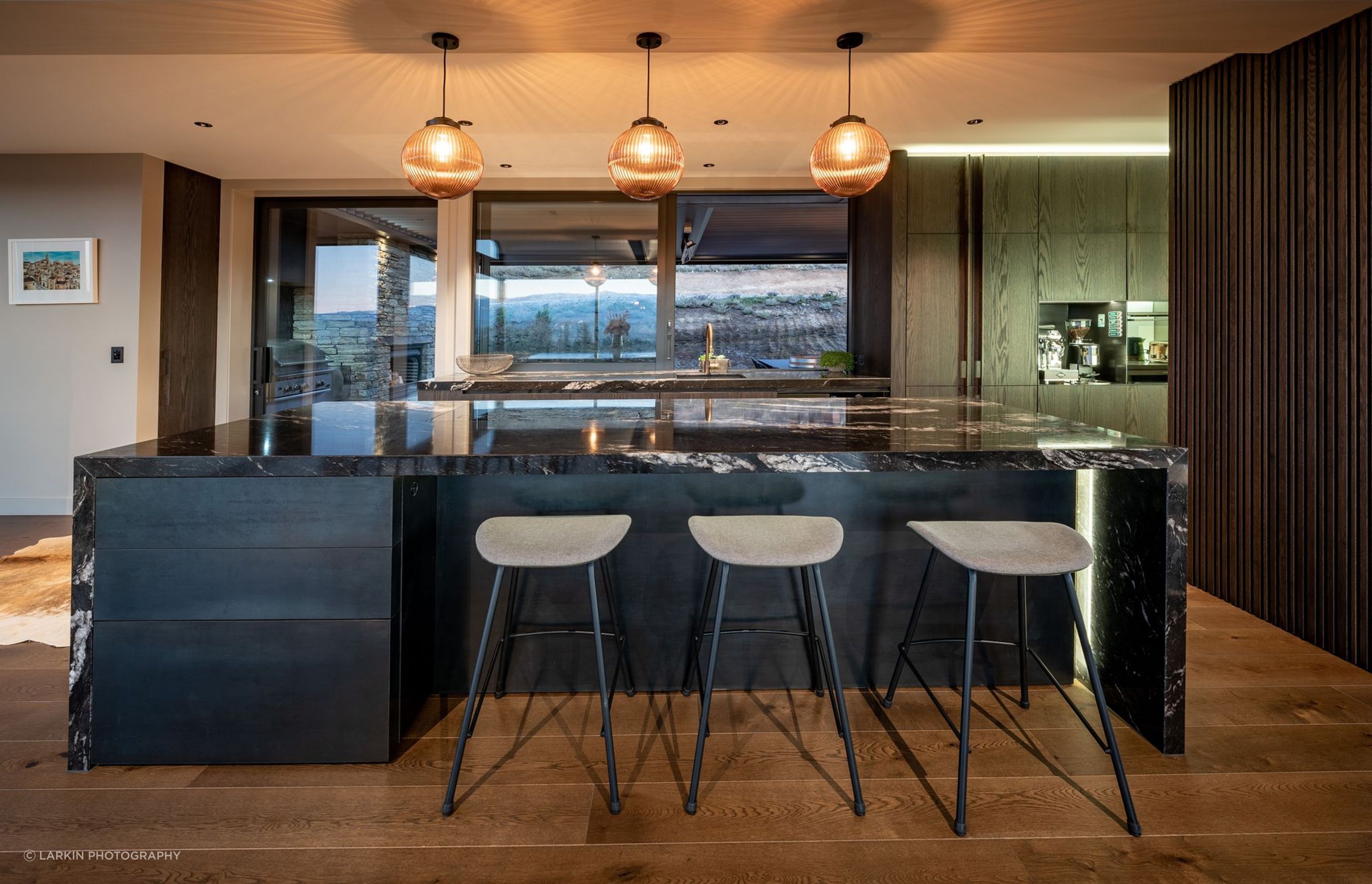 The dramatic granite kitchen island synchronises beautifully with the schist chimney in the covered courtyard space directly behind the kitchen.