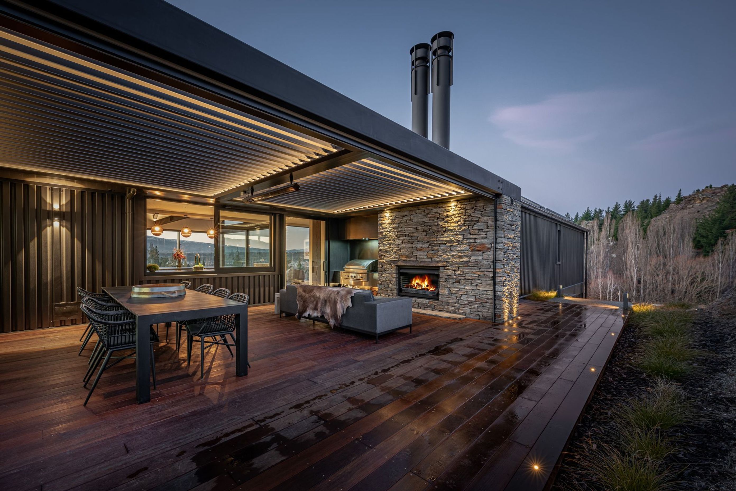At the rear of the house, adjacent to the kitchen, an external courtyard with schist fireplace and operable louvred roof provide a sheltered space outdoors to enjoy year-round.