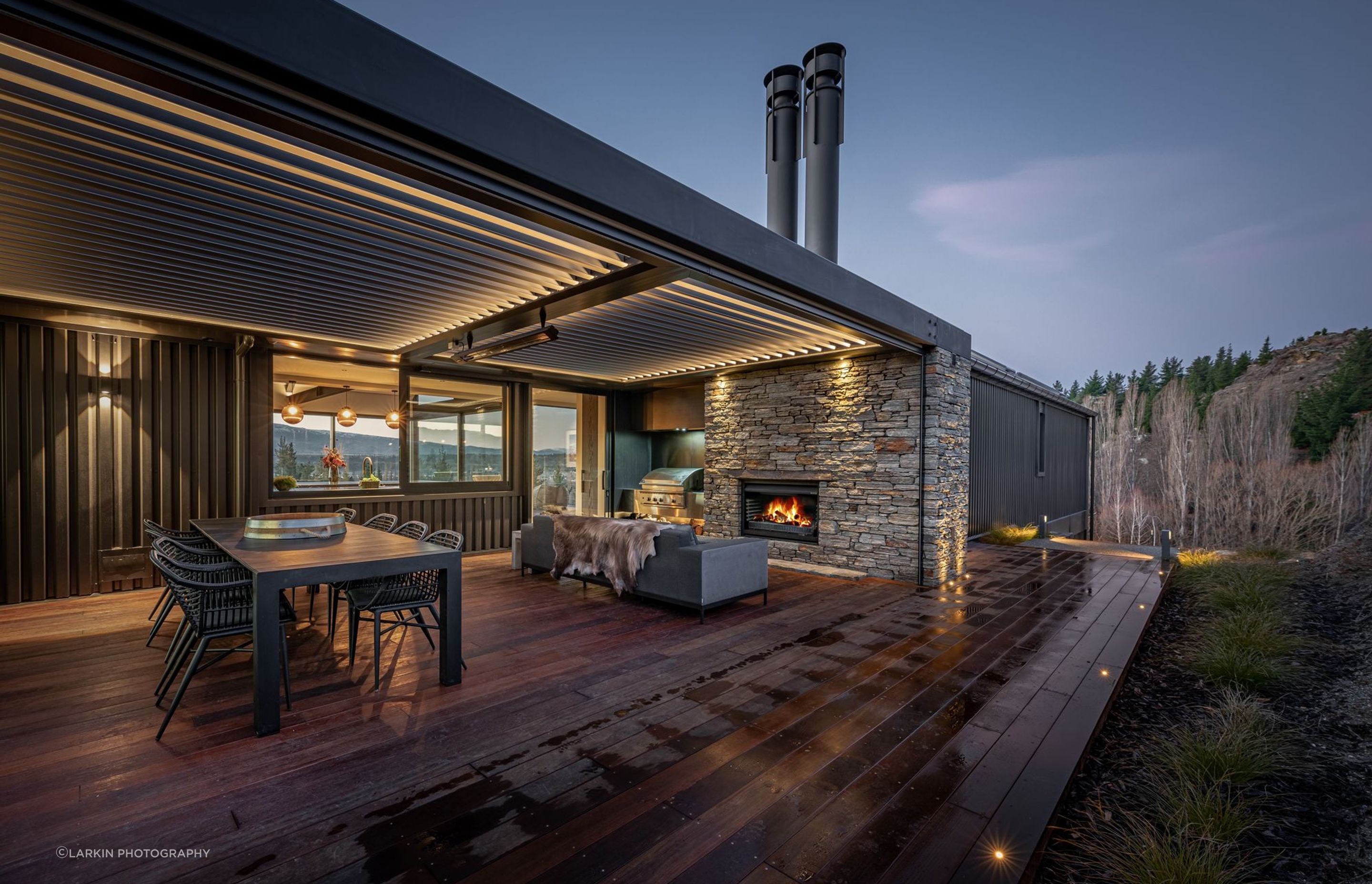 At the rear of the house, adjacent to the kitchen, an external courtyard with schist fireplace and operable louvred roof provide a sheltered space outdoors to enjoy year-round.