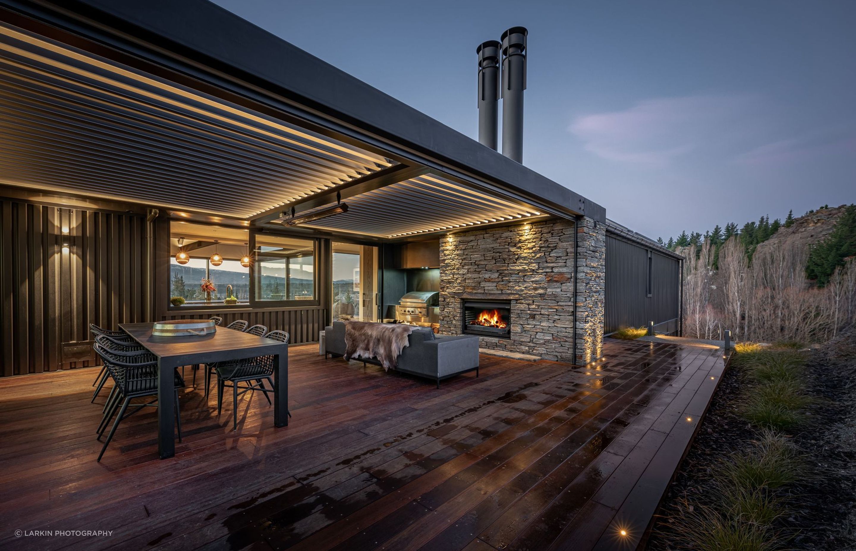 At the rear of the house, adjacent to the kitchen, an external courtyard with schist fireplace and operable louvred roof provide a sheltered space outdoors to enjoy year-round.