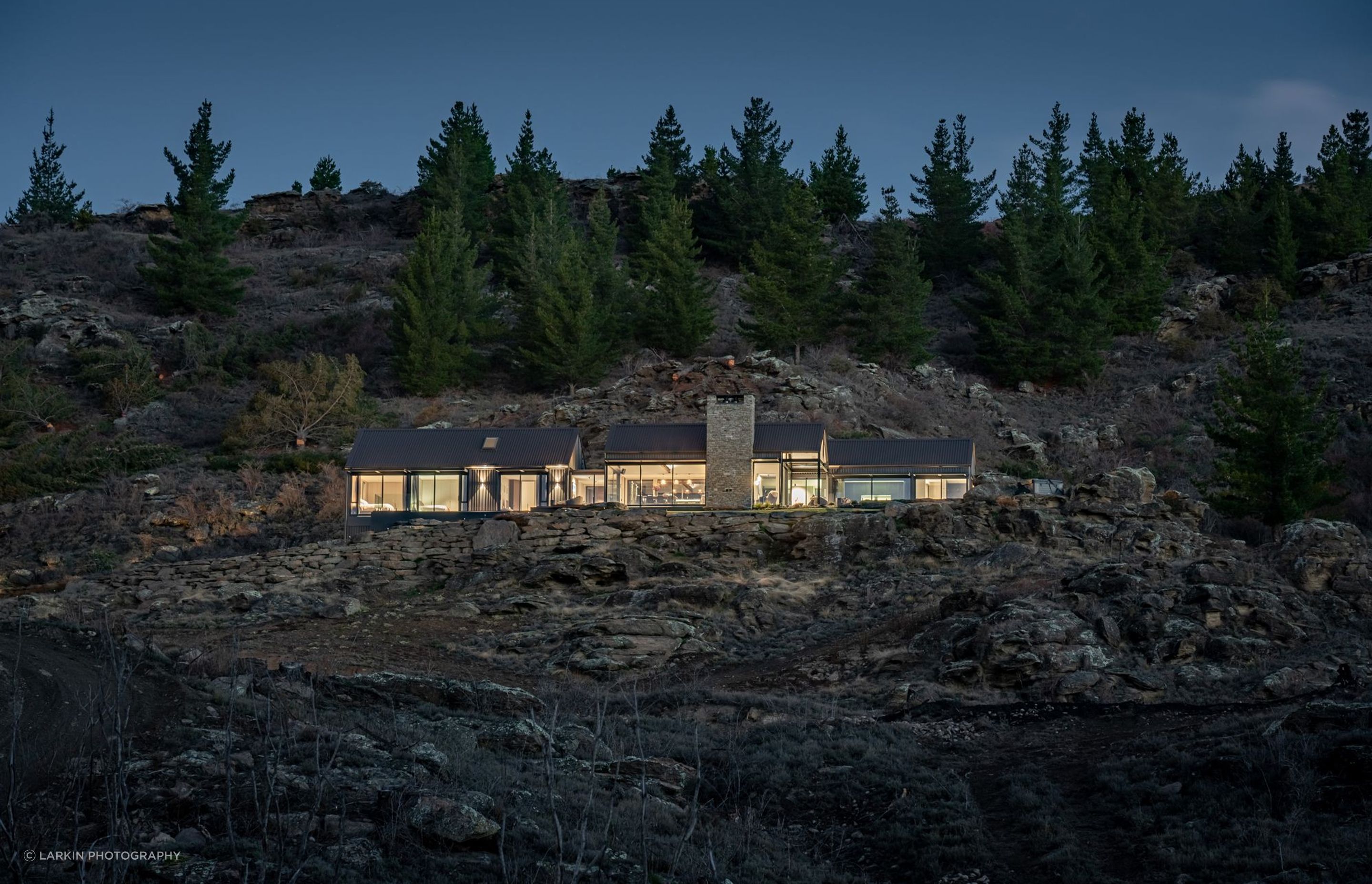 The journey to the home takes the visitor through a winding driveway of schist and poplar trees up to the left of the house, which contains a garage tucked under the bedroom wing.