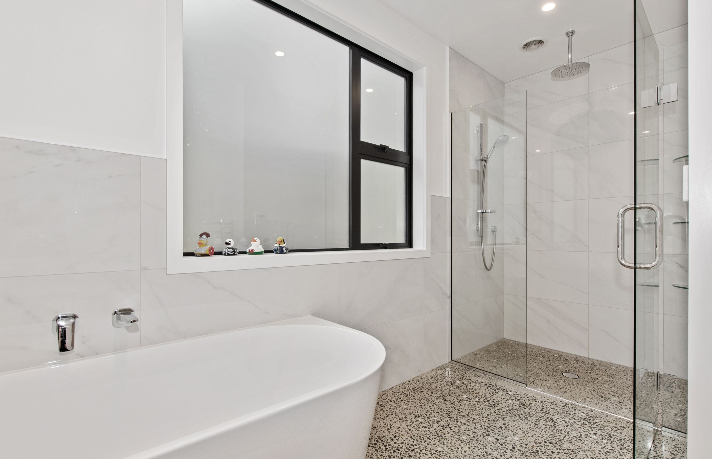 Family bathroom with polished concrete floor leading into tiled shower