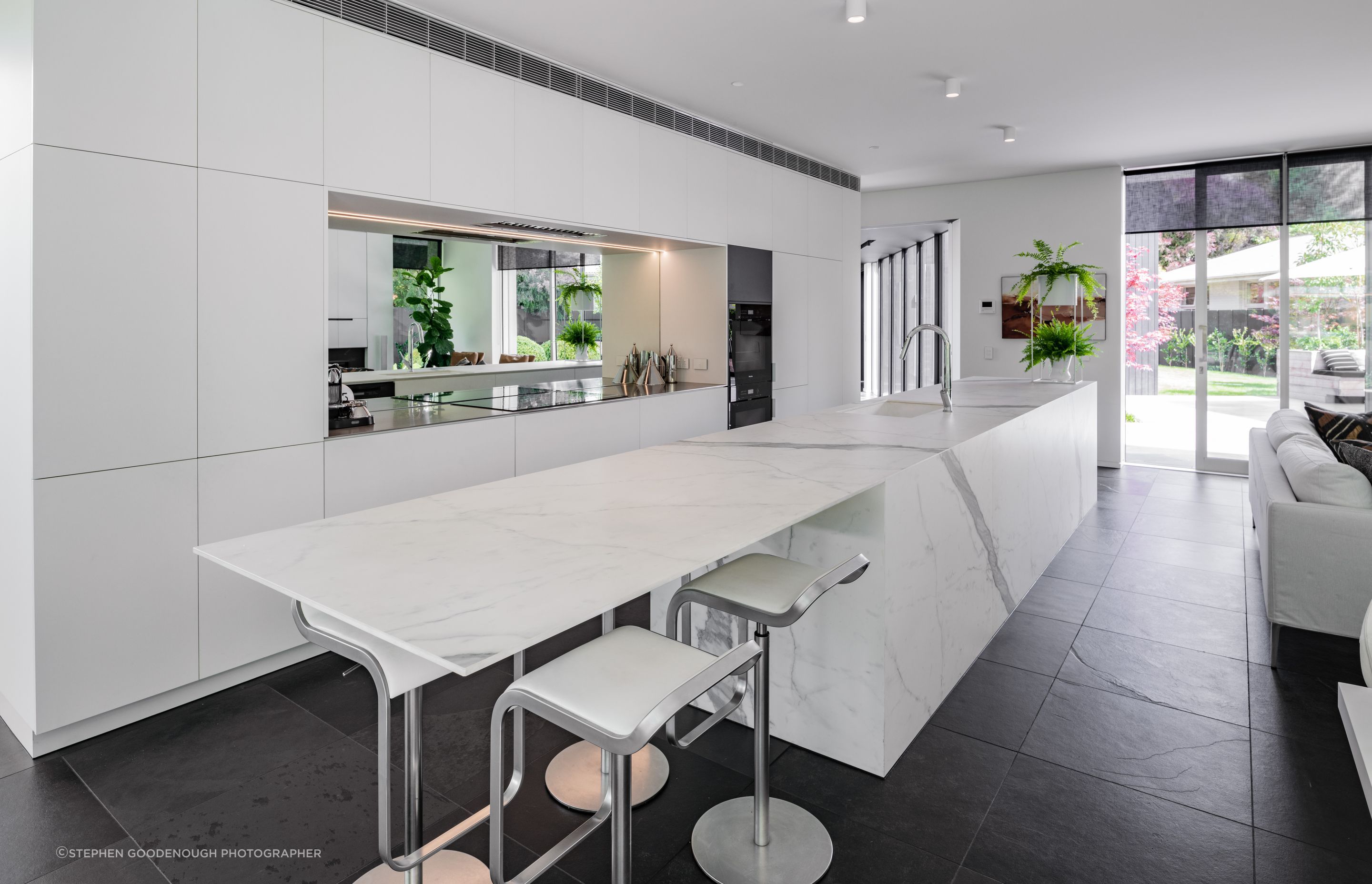 Open and airy, the kitchen features a mirrored splashback.
