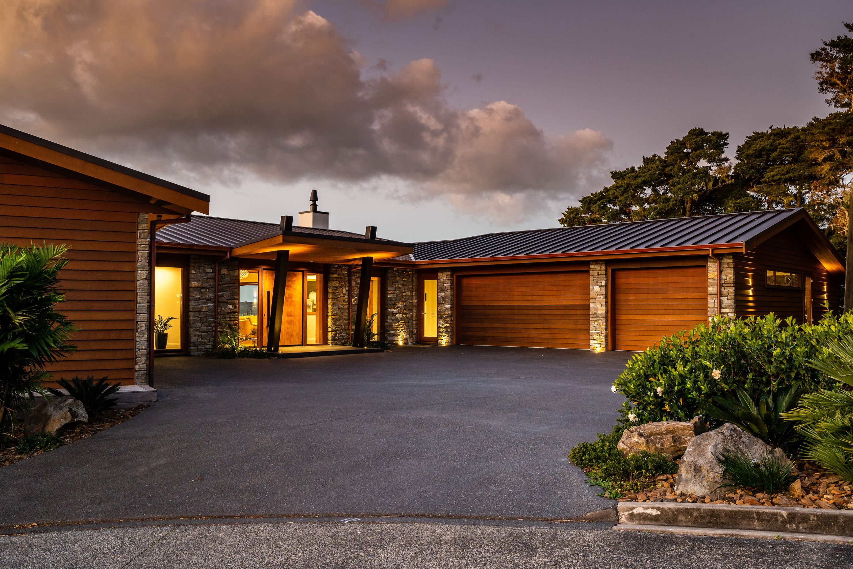 The house overlooking Paihia’s waterfront was built for a semi-retired couple. The pivot door is made from timber the homeowners had been saving. “We put a steel frame on it to stop it twisting because it’s so big,” says Alan Simpkin of Arcline Architecture. The homeowners requested a three-car garage, and the driveway required careful planning for vehicle movement as it exits to a narrow road on a hairpin bend.