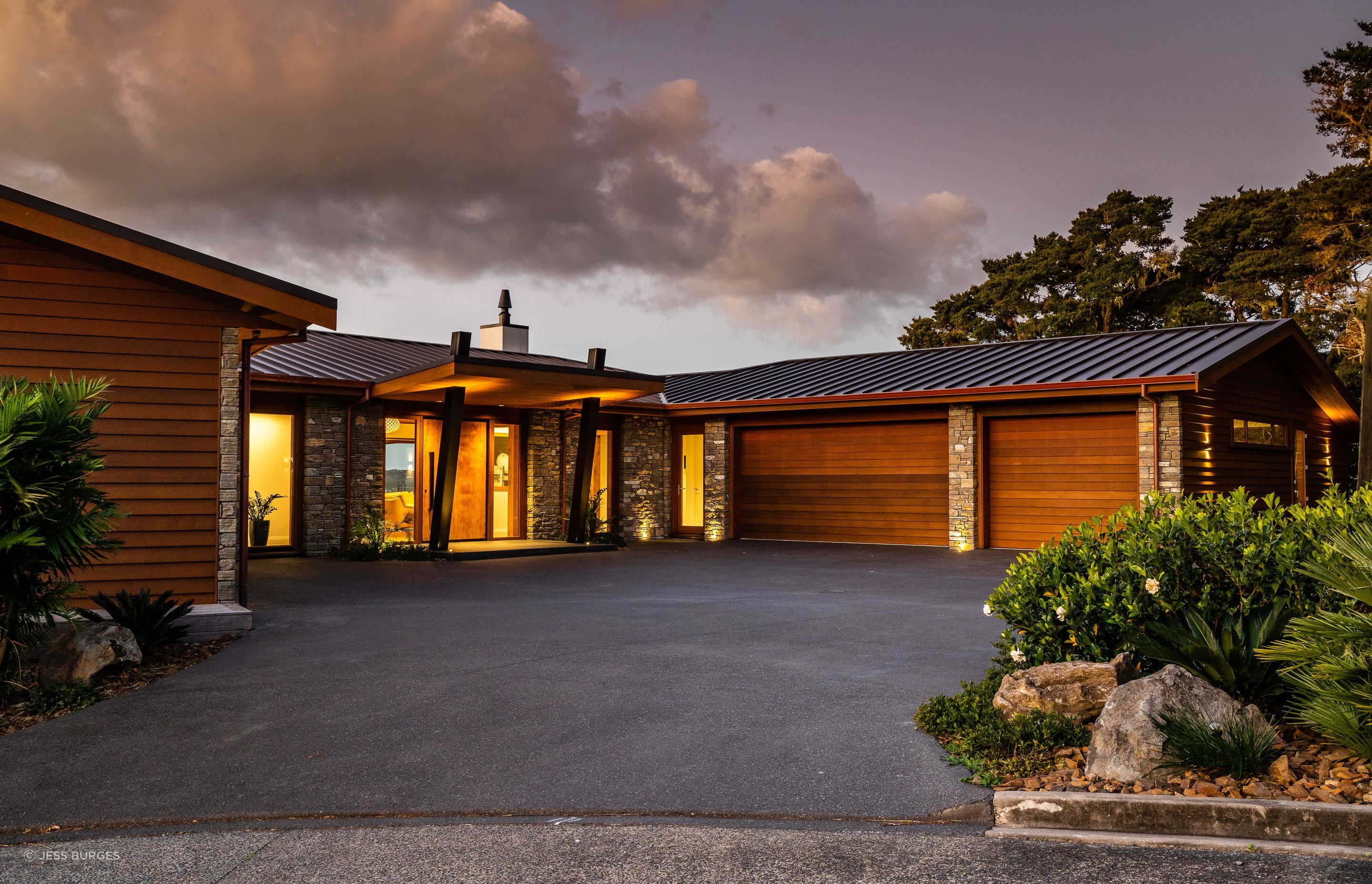 The house overlooking Paihia’s waterfront was built for a semi-retired couple. The pivot door is made from timber the homeowners had been saving. “We put a steel frame on it to stop it twisting because it’s so big,” says Alan Simpkin of Arcline Architecture. The homeowners requested a three-car garage, and the driveway required careful planning for vehicle movement as it exits to a narrow road on a hairpin bend.
