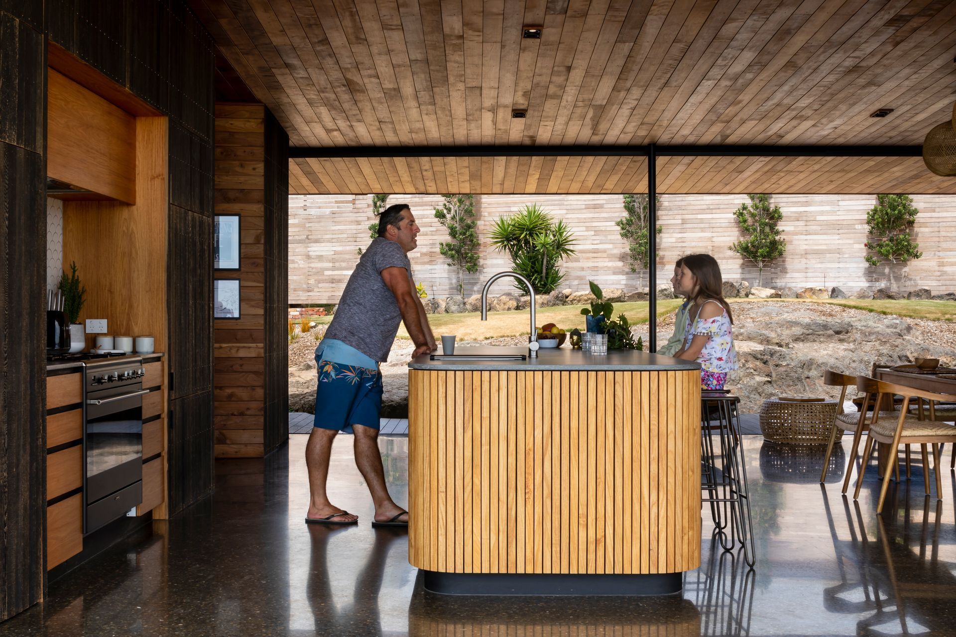 Ken serves his daughters at the kitchen island; the family home has spectacular indoor-outdoor flow for ease of family life.