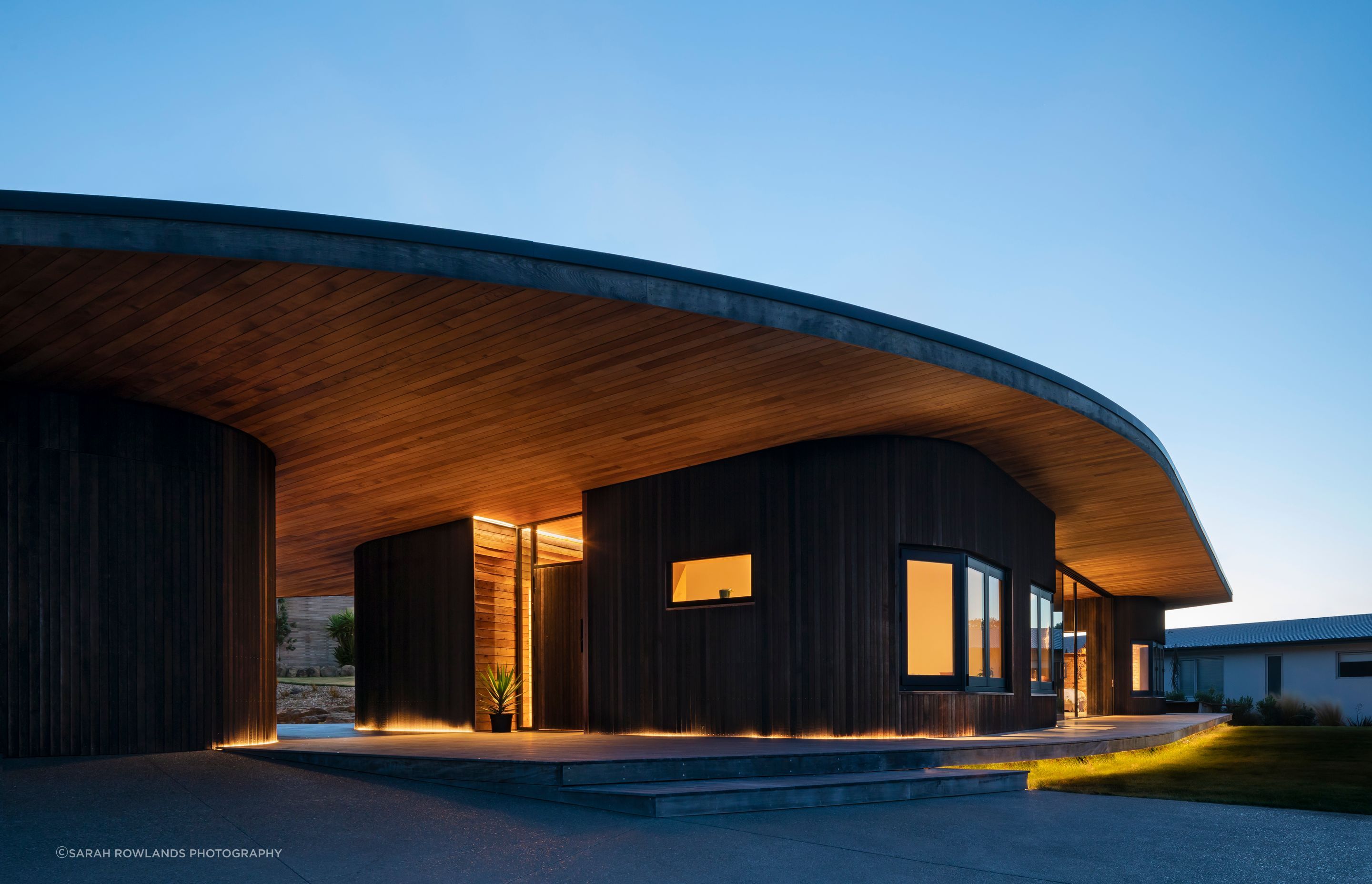 The curved roof lifts to frame the view and hunkers down at each end of the house to provide privacy from neighbours.