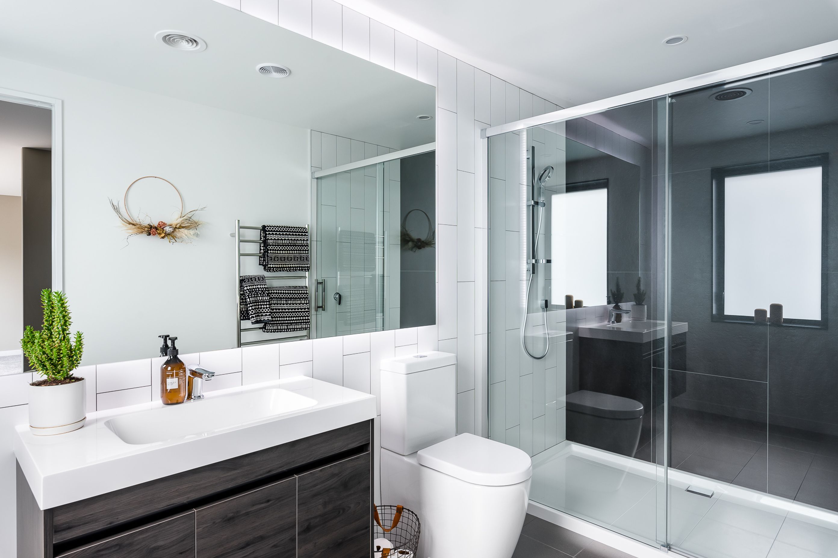 Verticality once again makes an appearance in the main ensuite while the dichromatic colour scheme imparts a very modern feel. The timber-look finish on the vanity references the home's intimate link to its environment.