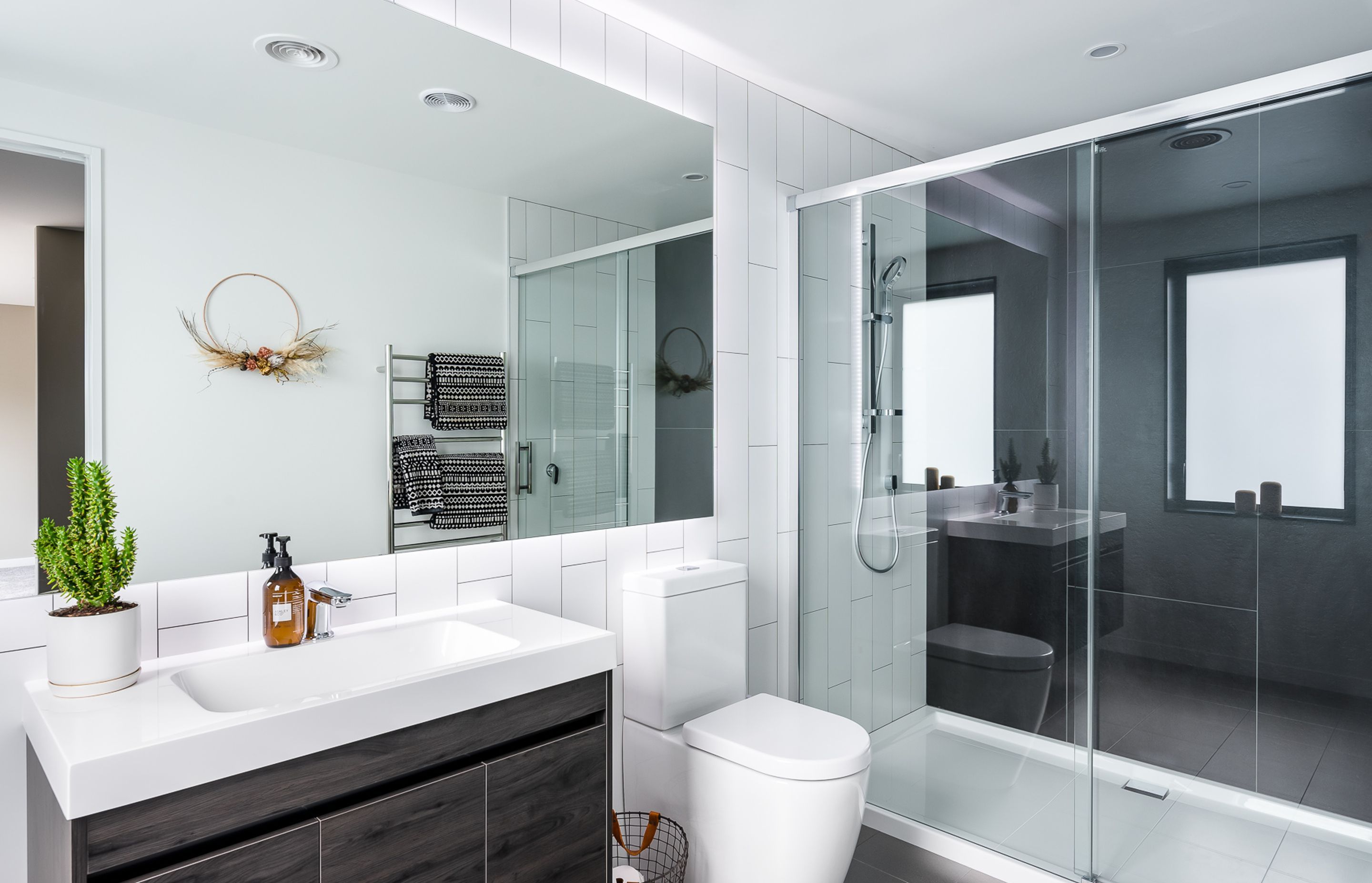 Verticality once again makes an appearance in the main ensuite while the dichromatic colour scheme imparts a very modern feel. The timber-look finish on the vanity references the home's intimate link to its environment.