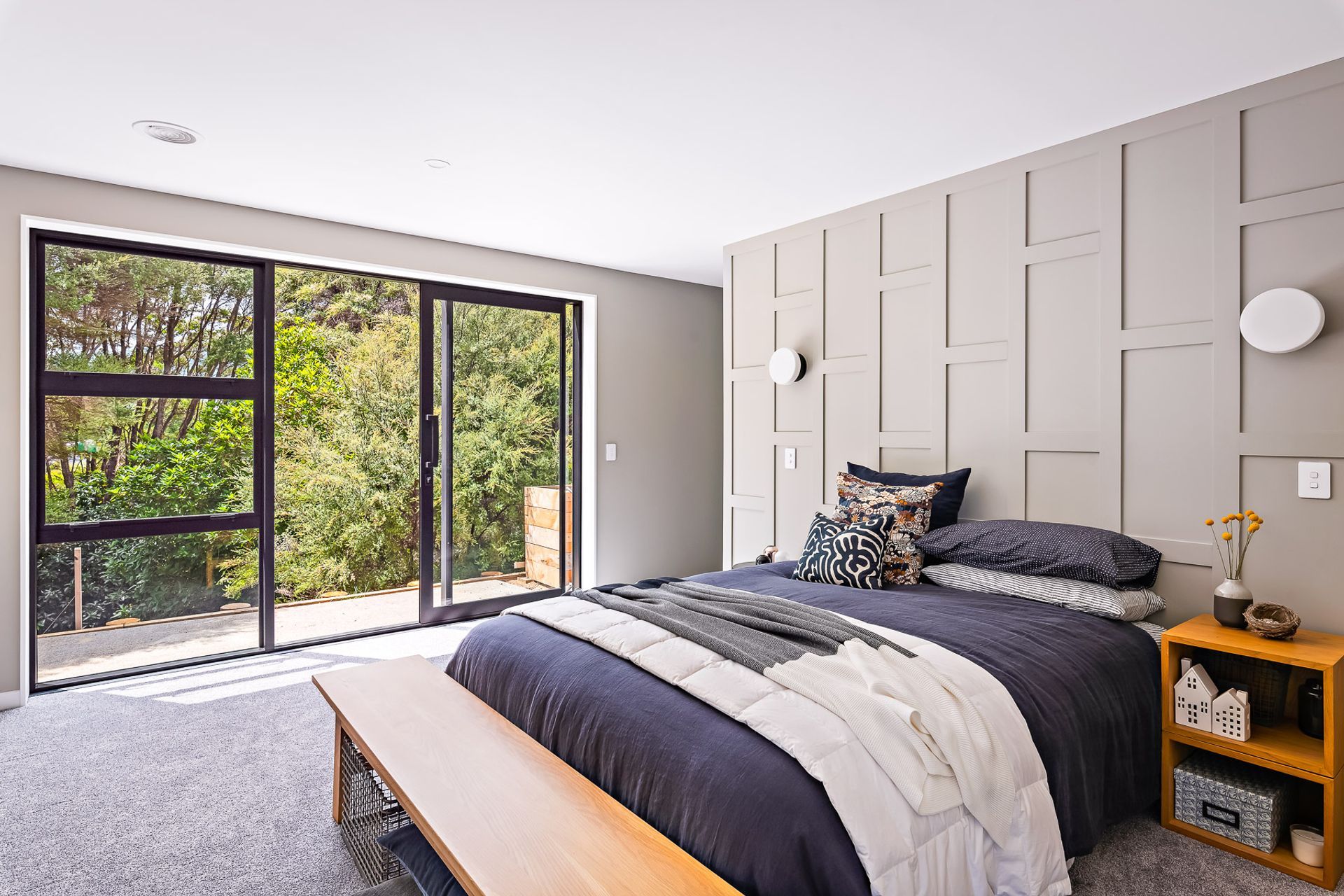 The main bedroom enjoys a backdrop of native kānuka and opens out onto a private courtyard space for morning sun.