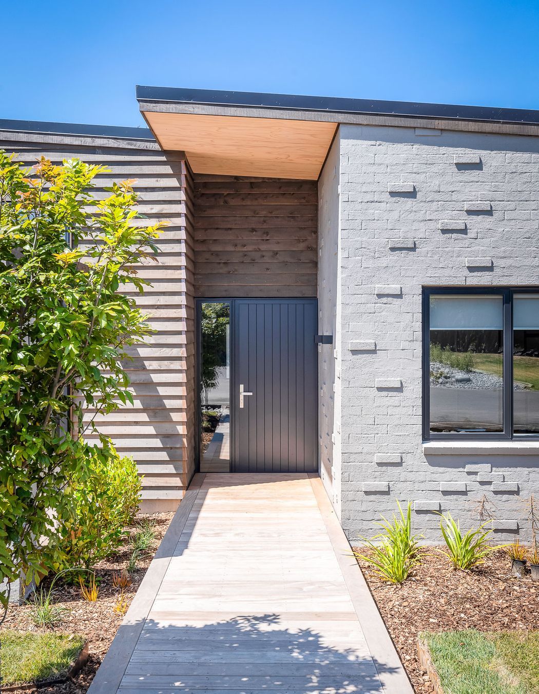 Stepped-back within the building's envelope, the recessed nature of the front door hints at a home that has been designed to offer a comforting welcome after a long day.