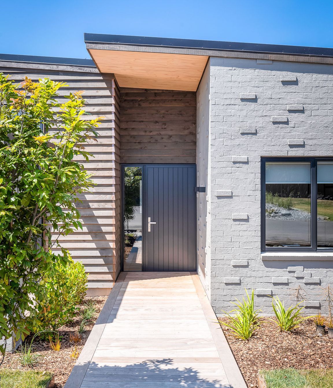Stepped-back within the building's envelope, the recessed nature of the front door hints at a home that has been designed to offer a comforting welcome after a long day.