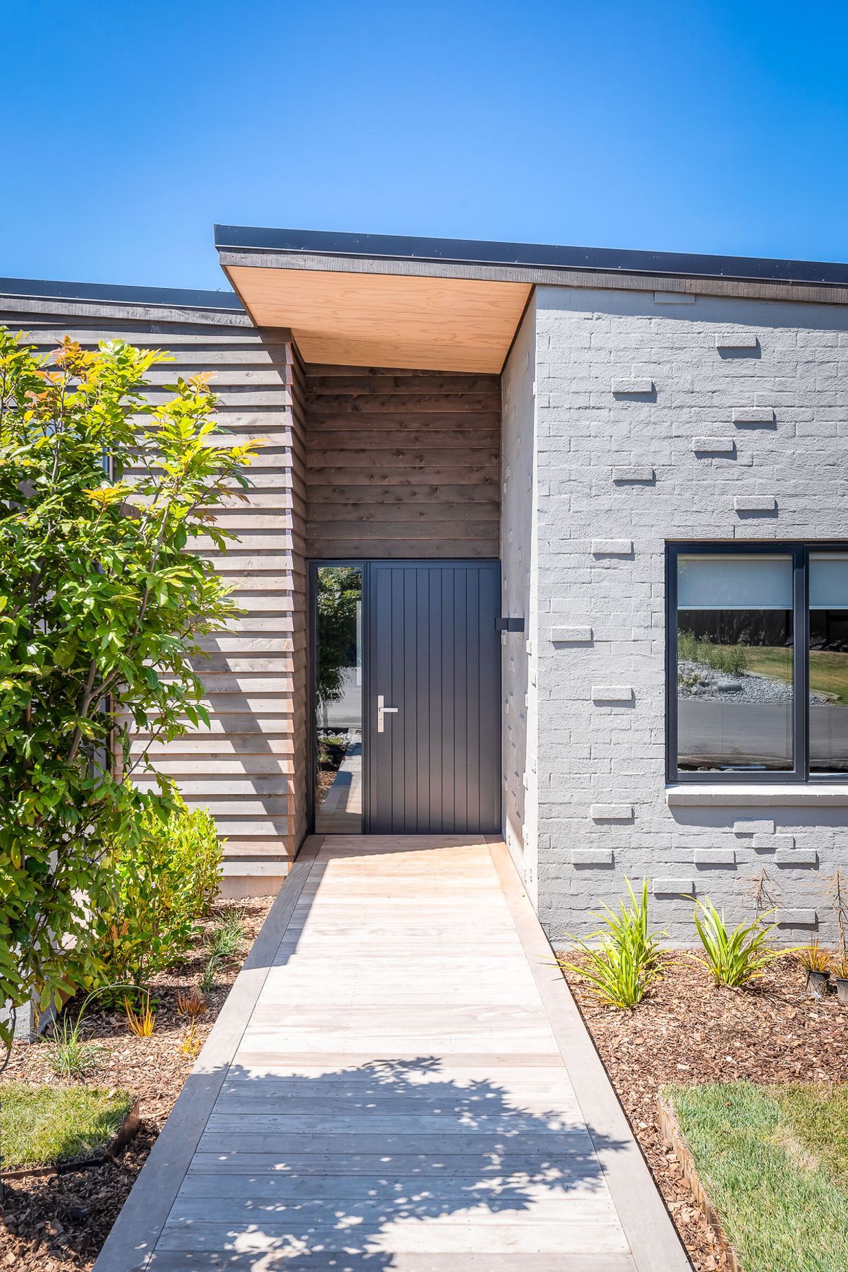 Stepped-back within the building's envelope, the recessed nature of the front door hints at a home that has been designed to offer a comforting welcome after a long day.