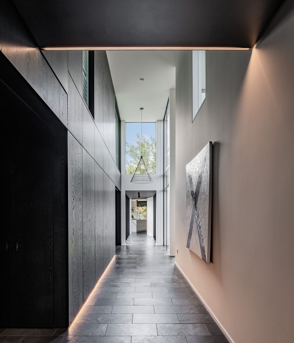 A spine of dark cabinetry conceals the home's private spaces.